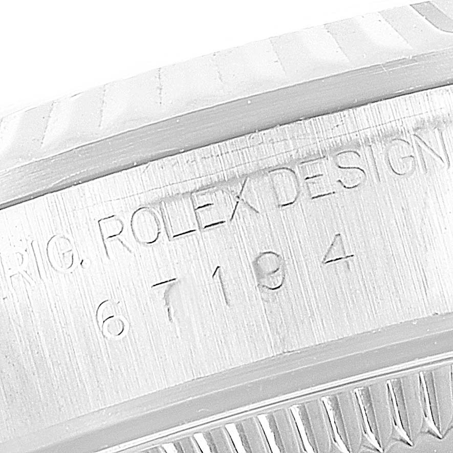 The image shows a close-up of the engraved case side of the Rolex Oyster Perpetual 67194 Women's Stainless Steel Black Dial 67194 Women's Stainless Steel Black Dial watch, displaying the serial number and design information.