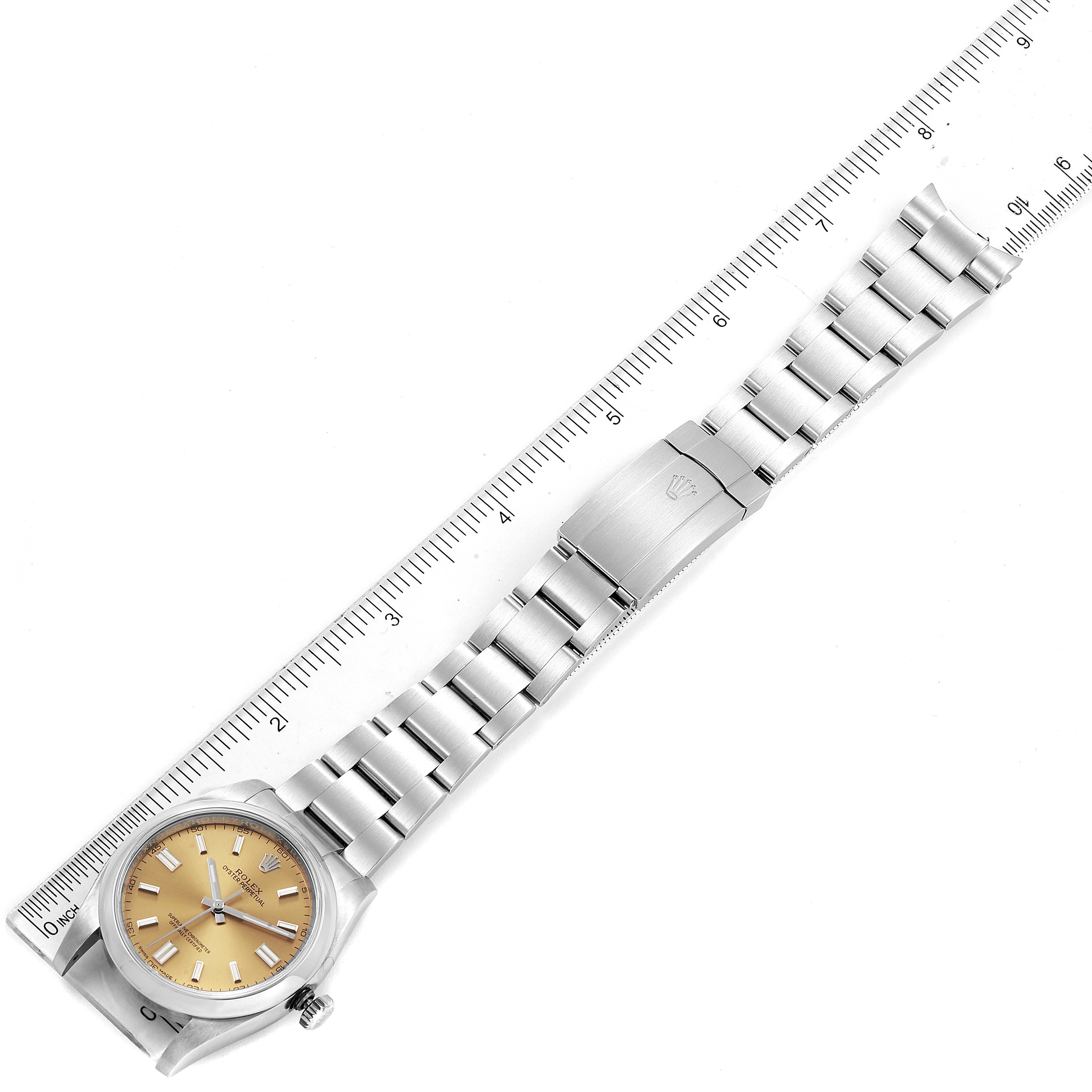 The image shows the Rolex Oyster Perpetual 116000 Men's Stainless Steel Champagne Dial 116000 Men's Stainless Steel Champagne Dial watch laid flat, displaying the dial, bracelet, and clasp next to a ruler for scale.