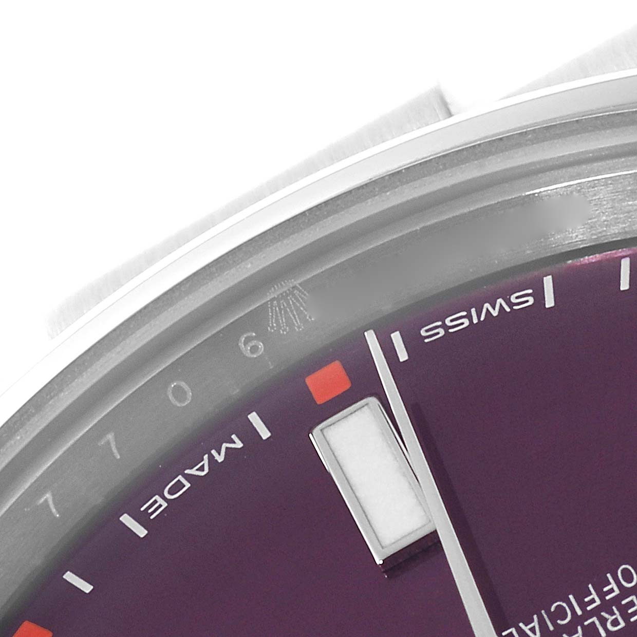 This close-up angle of the Rolex Oyster Perpetual 114300 Men's Stainless Steel Burgundy Dial 114300 Men's Stainless Steel Burgundy Dial watch shows the edge of the dial, hour markers, and partial text.