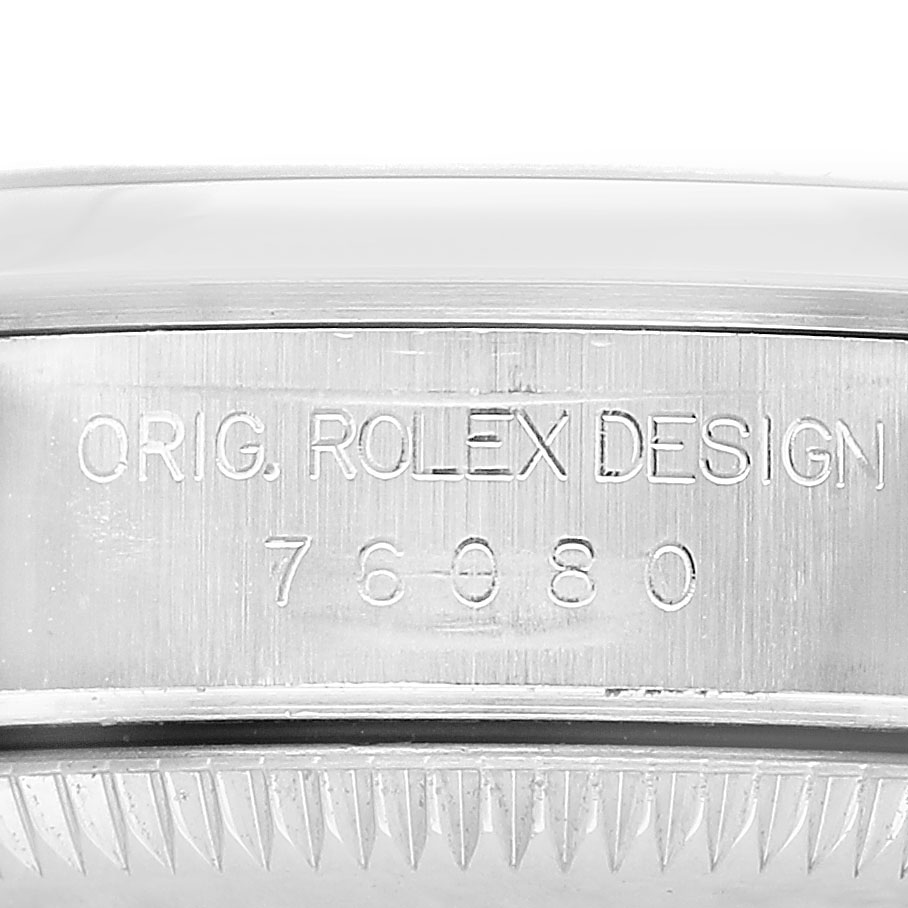The image shows the side of a Rolex Oyster Perpetual 76080 Women's Stainless Steel Black Dial watch case, highlighting the engraved design and model number.