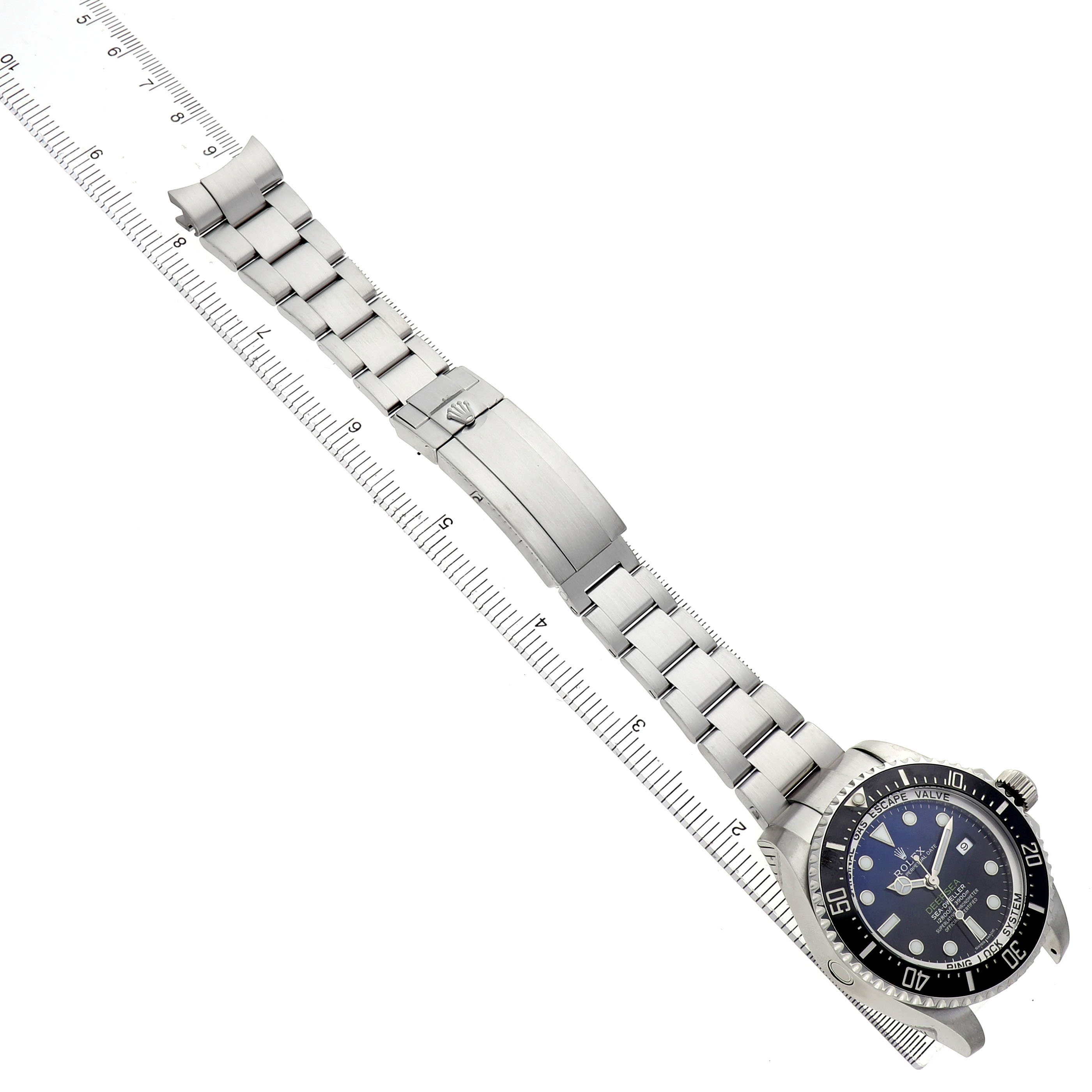 The Rolex Sea-Dweller 116660 Men's Stainless Steel Blue Dial watch is shown from a top view, displaying the full bracelet, clasp, and bezel, aligned with a ruler.