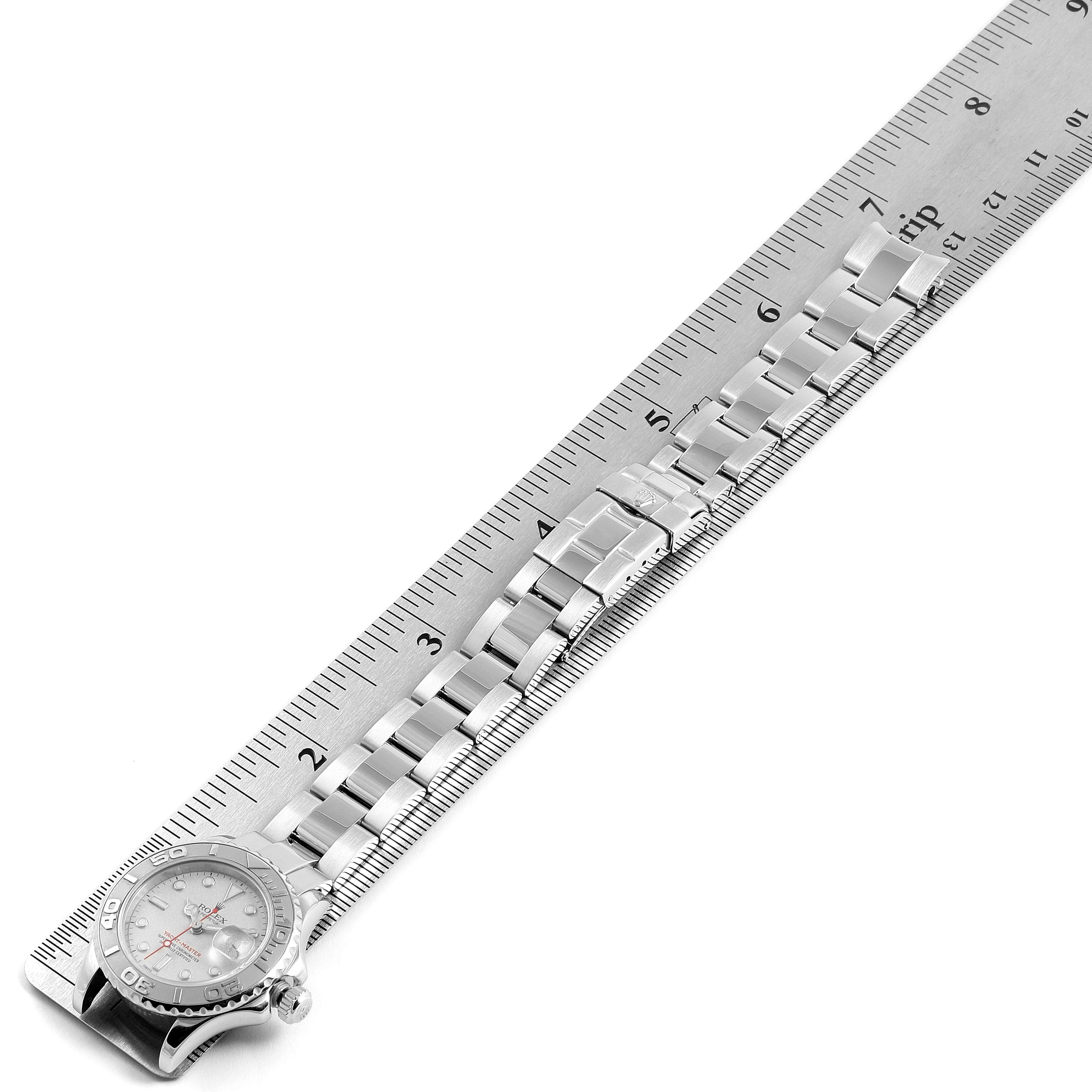 The image shows the Rolex Yacht-Master 169622 Women's Stainless Steel Silver Dial 169622 Women's Stainless Steel Silver Dial watch laid flat with a metal band, aligned beside a ruler.