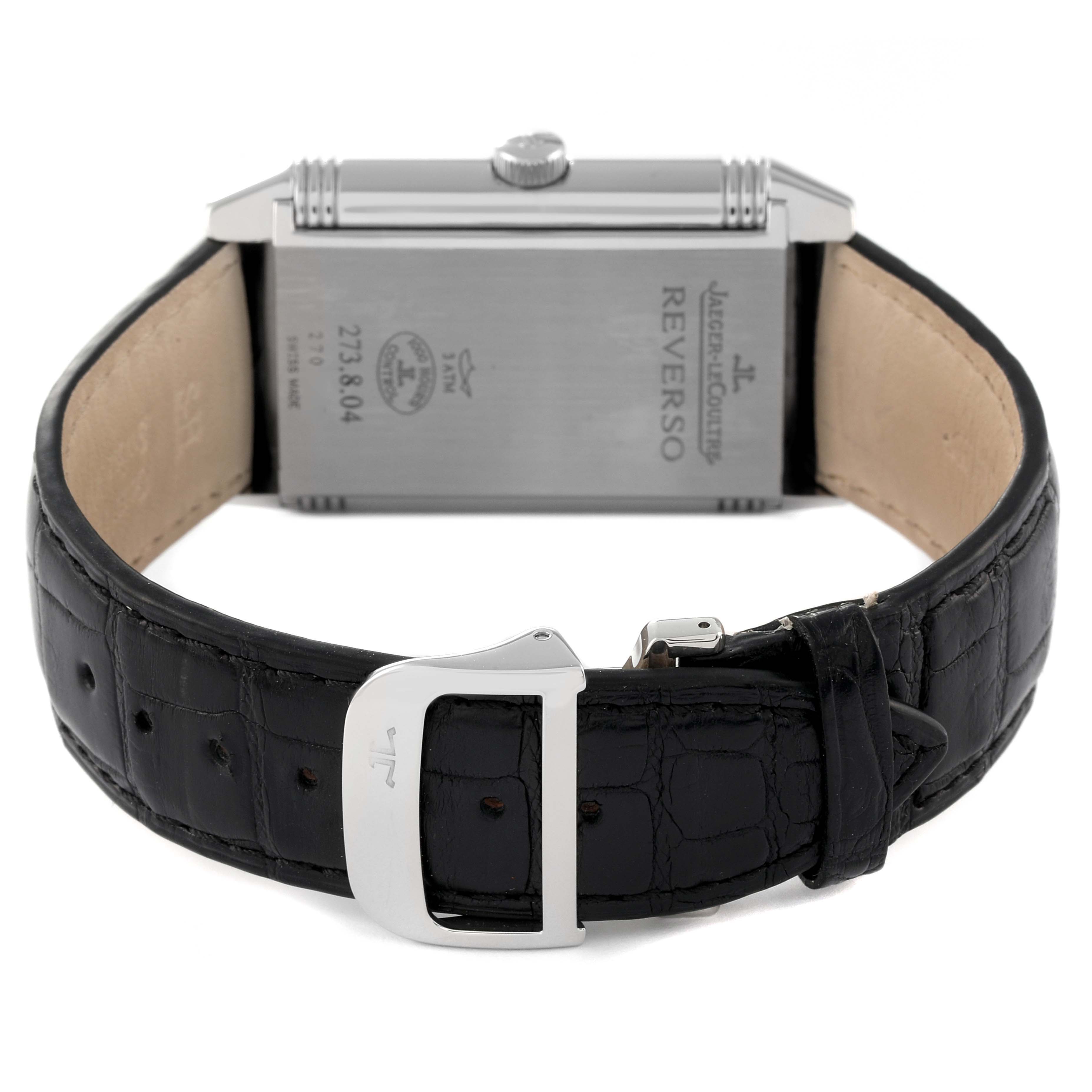 The image shows the back view of a Jaeger-LeCoultre Reverso watch, displaying its back case, crown, and black leather strap with buckle.