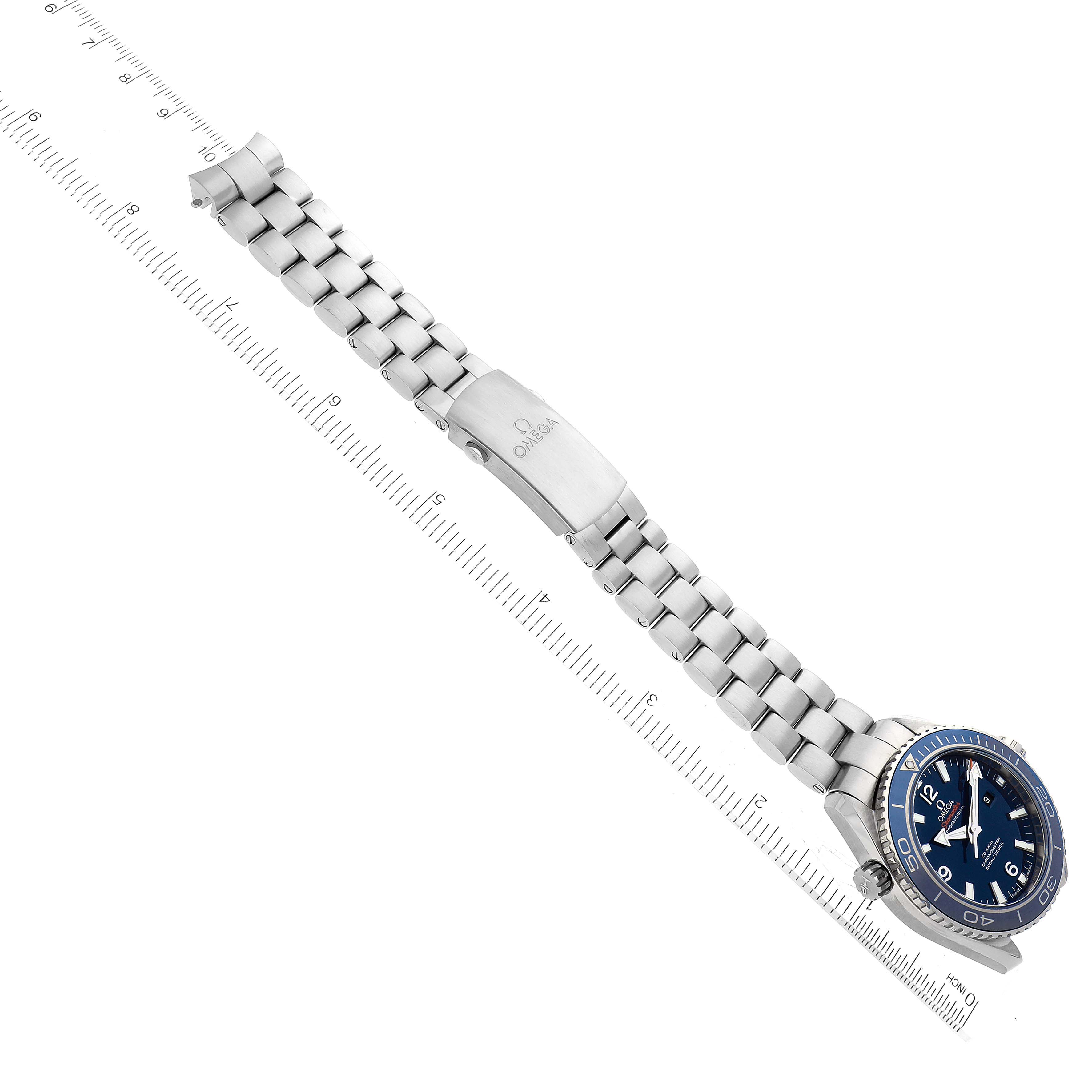 The Omega Planet Ocean 232.90.38.20.03.001 Men's Titanium Blue Dial watch is shown at an angle highlighting the dial and bracelet extended alongside a ruler.