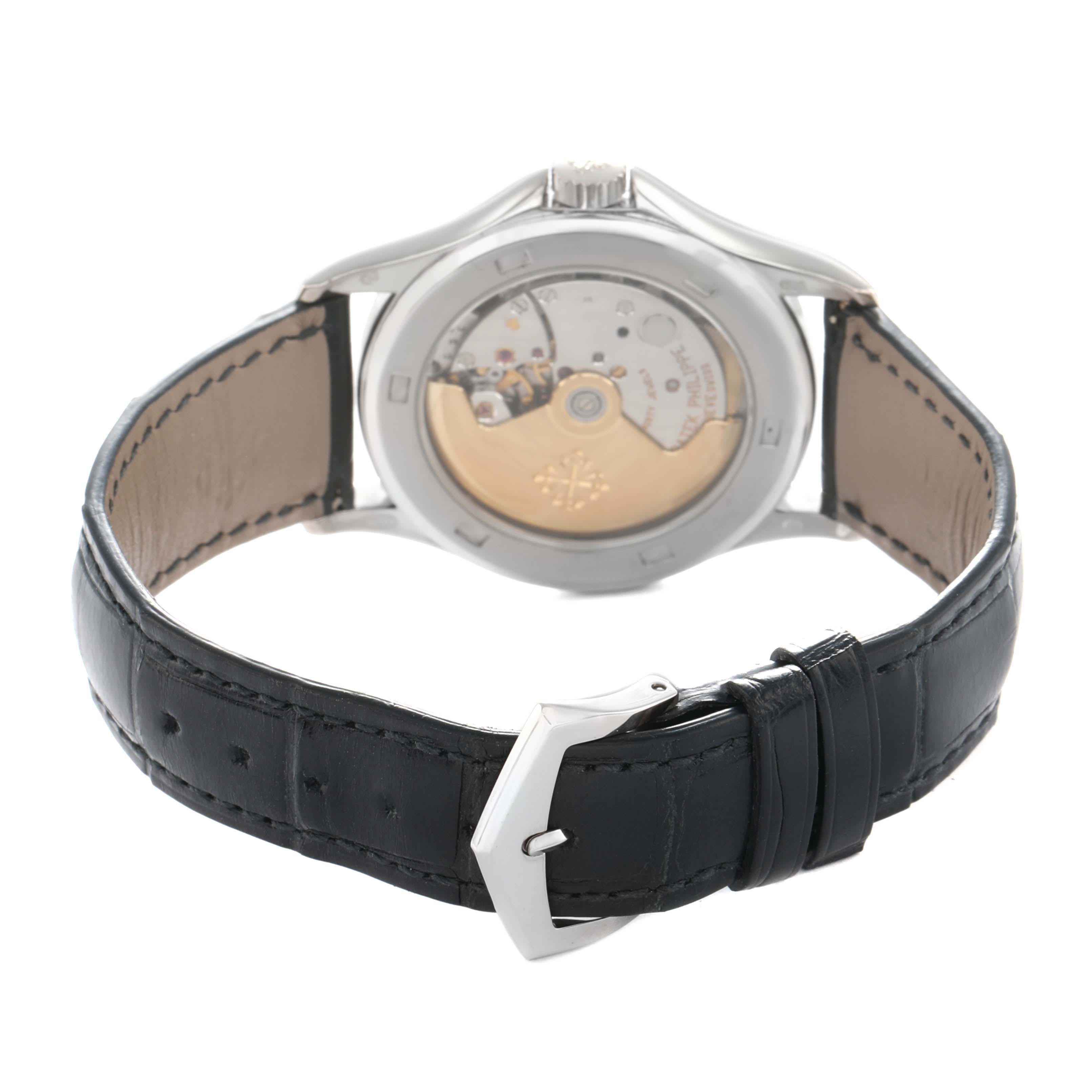The image shows the back view of a Patek Philippe Calatrava 5117G Men
s White Gold White Dial watch, highlighting the movement and the leather strap with a buckle.