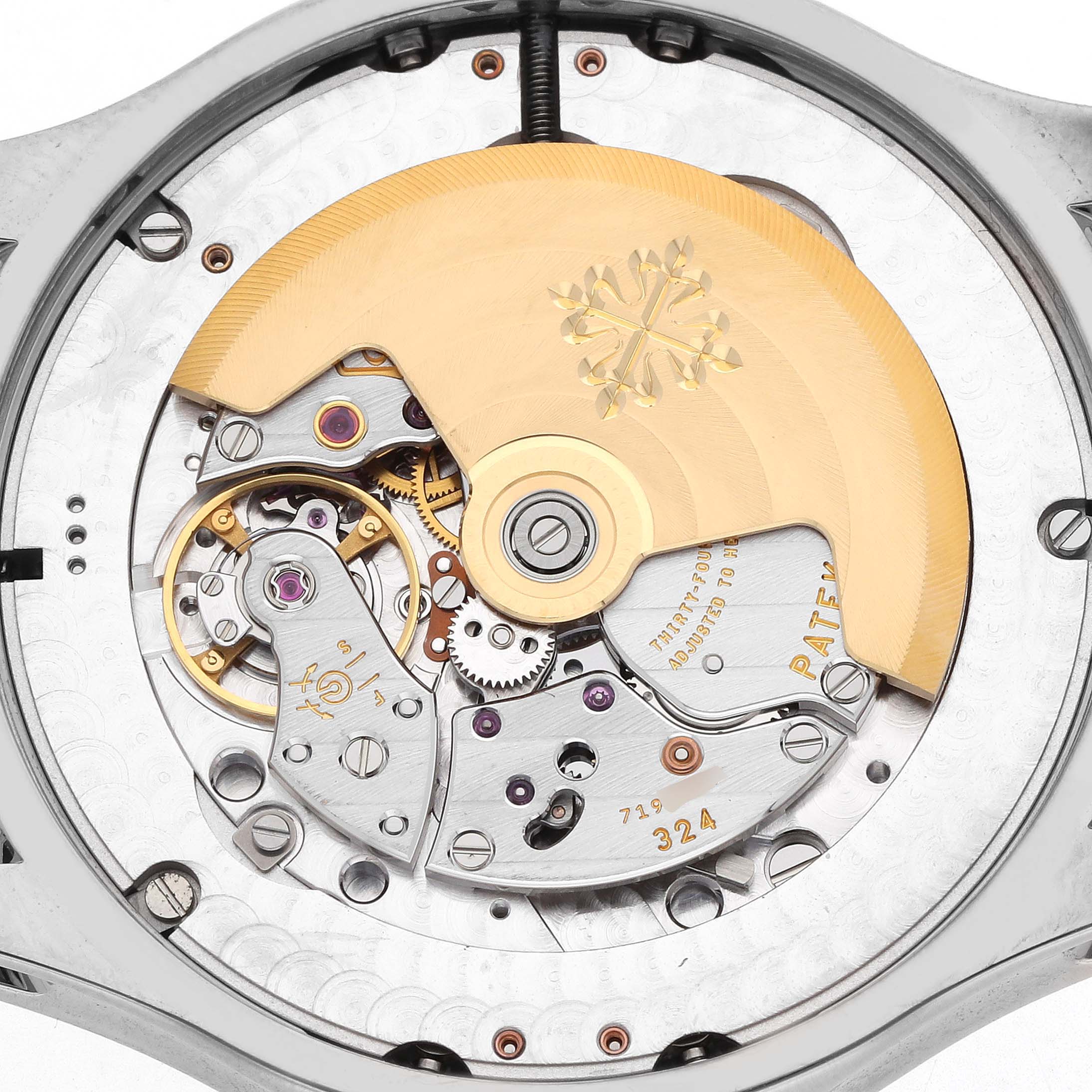 The image shows a close-up view of the movement of a Patek Philippe Complications 5205G-013 Men
s White Gold Blue Dial watch, highlighting the rotor and intricate mechanics.