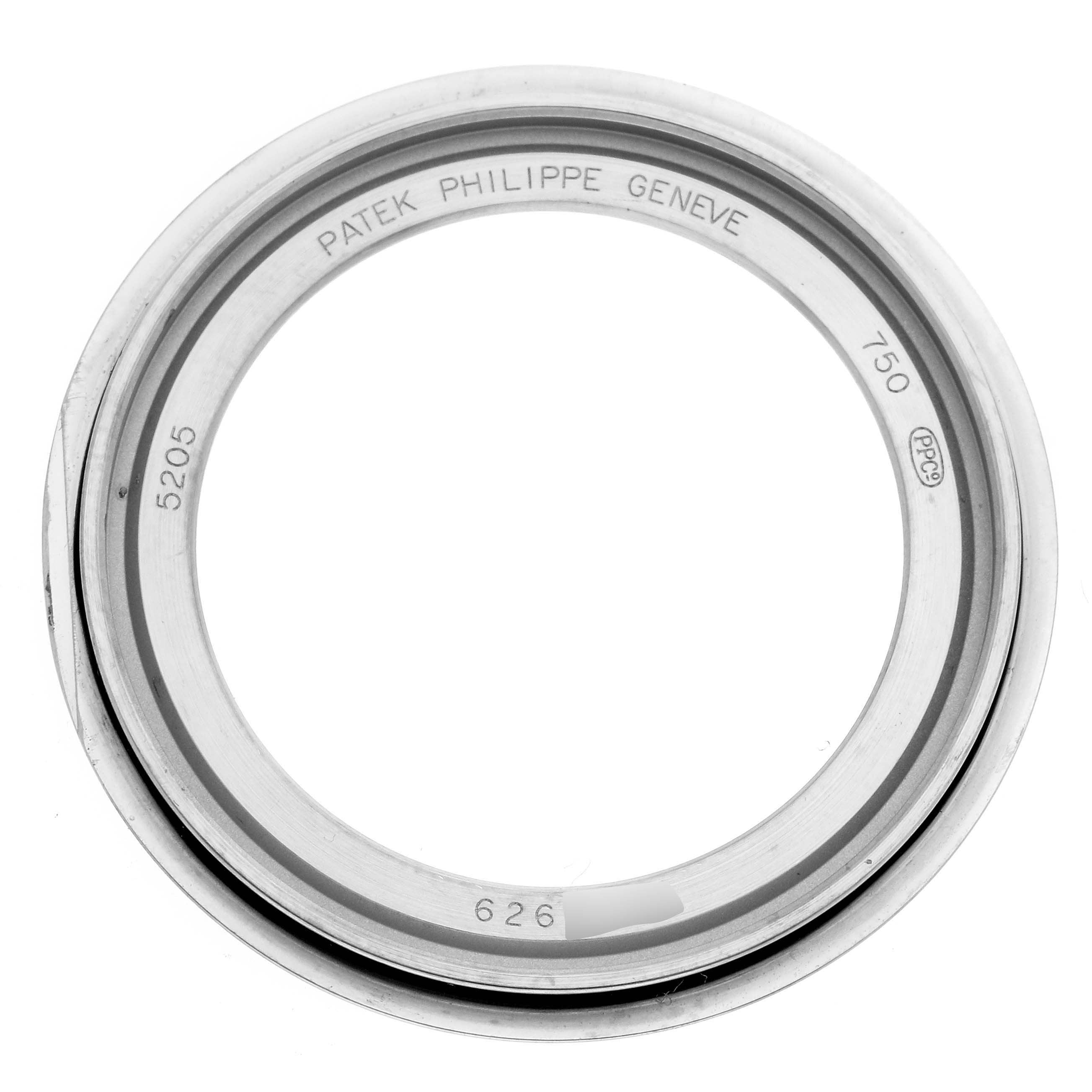 The image shows a top-down view of a Patek Philippe Complications 5205G-013 Men
s White Gold Blue Dial watch bezel, with engravings and hallmark visible.