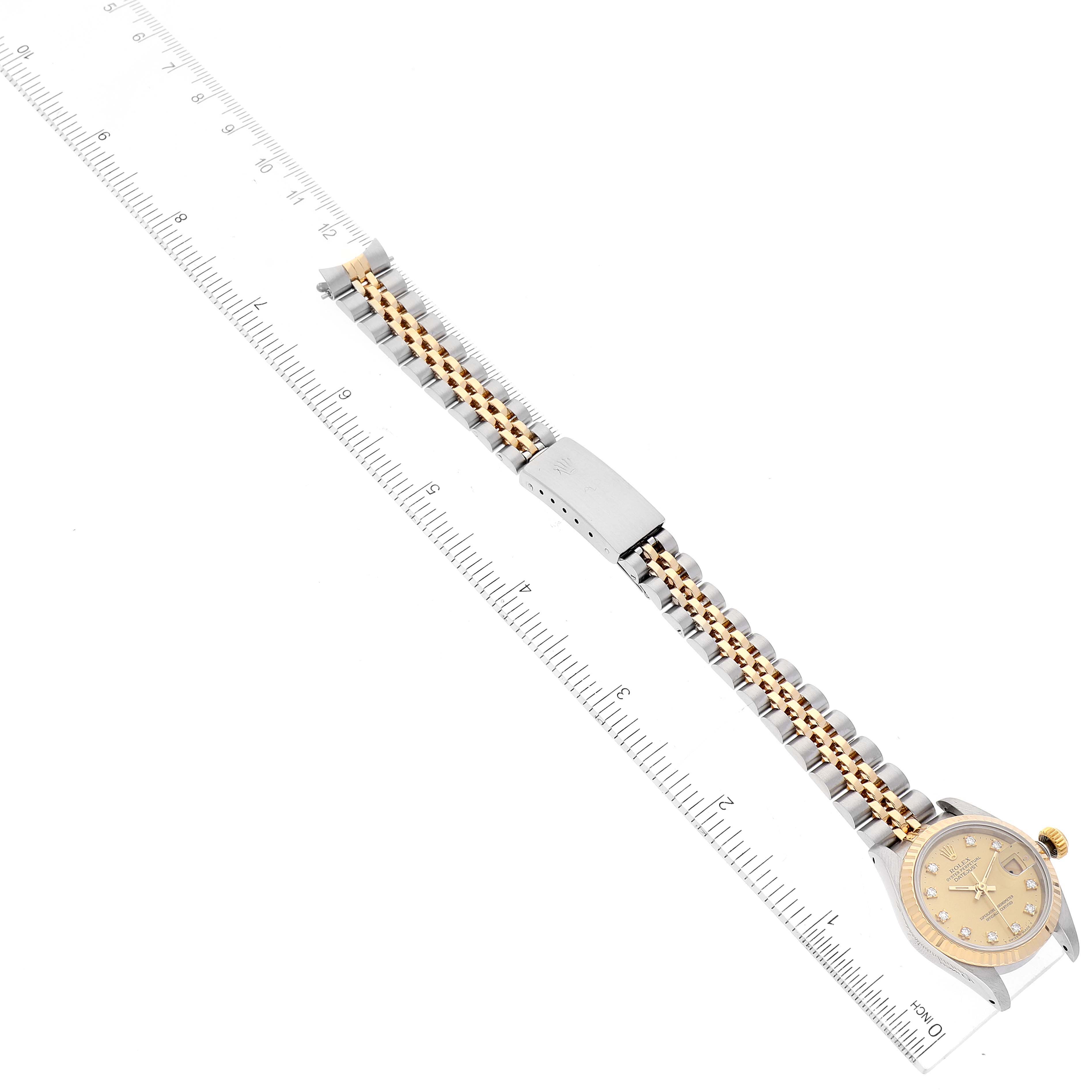 The image shows a Rolex Datejust 69173 Women's Steel and Gold (two tone) Champagne Dial 69173 Women's Steel and Gold (two tone) Champagne Dial watch from a top-down angle, highlighting its face and entire metal bracelet placed alongside a ruler.