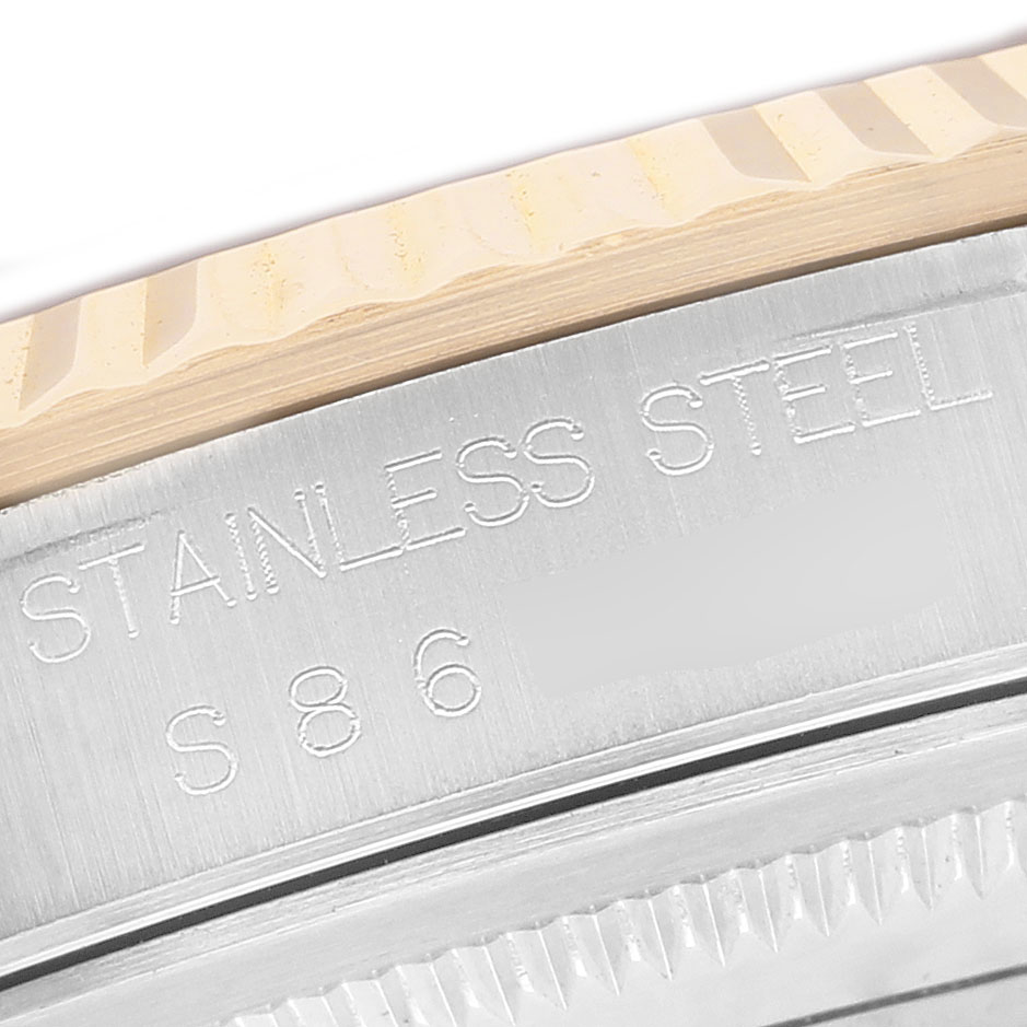 The image shows a close-up of the fluted bezel and engraved case of a Rolex Datejust 16233 Men's Steel and Gold (two tone) Blue Dial watch.