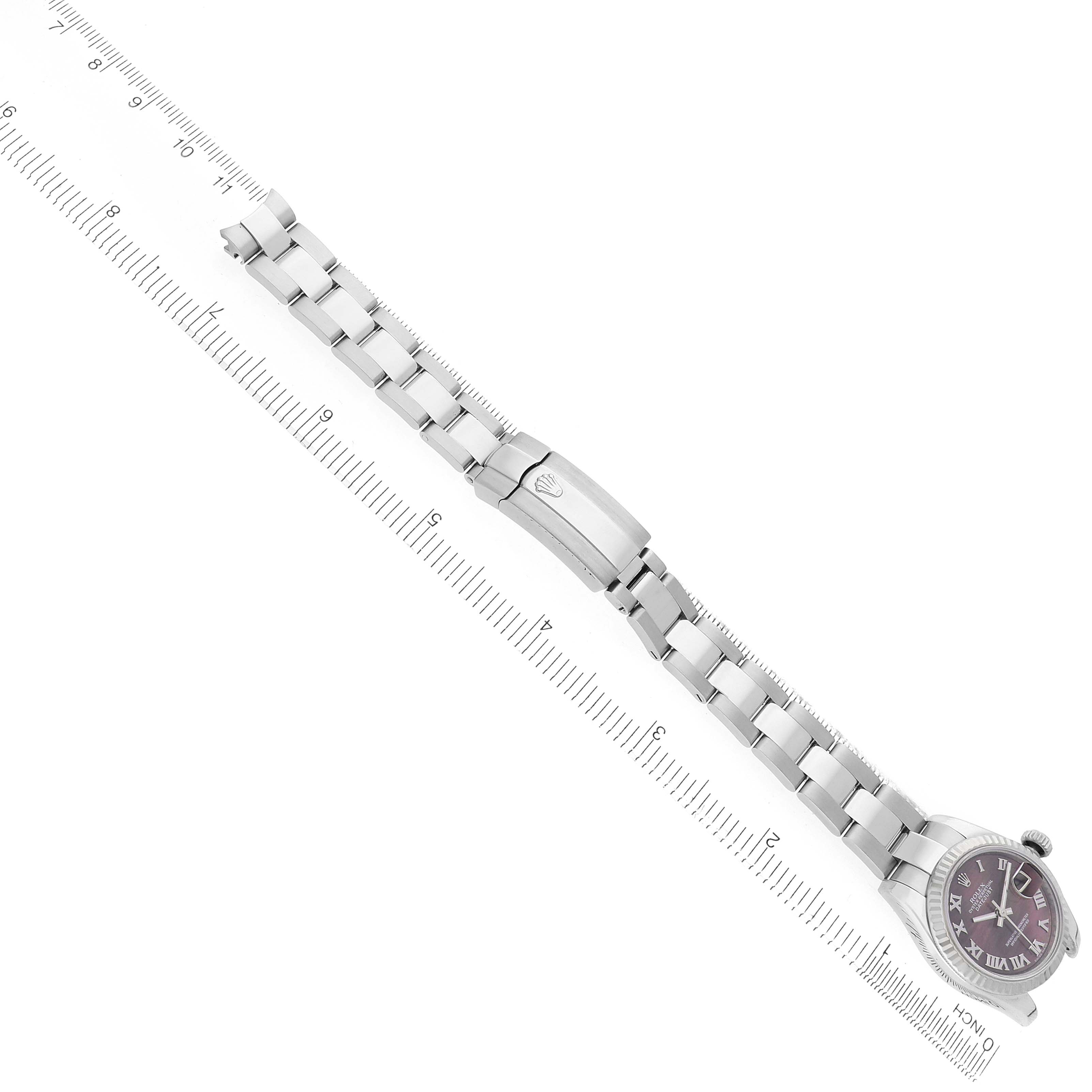 The Rolex Datejust 179174 Men
s Stainless Steel Mother of Pearl Dial watch is shown from an angle showcasing the bracelet and clasp, aligned with a ruler for scale.