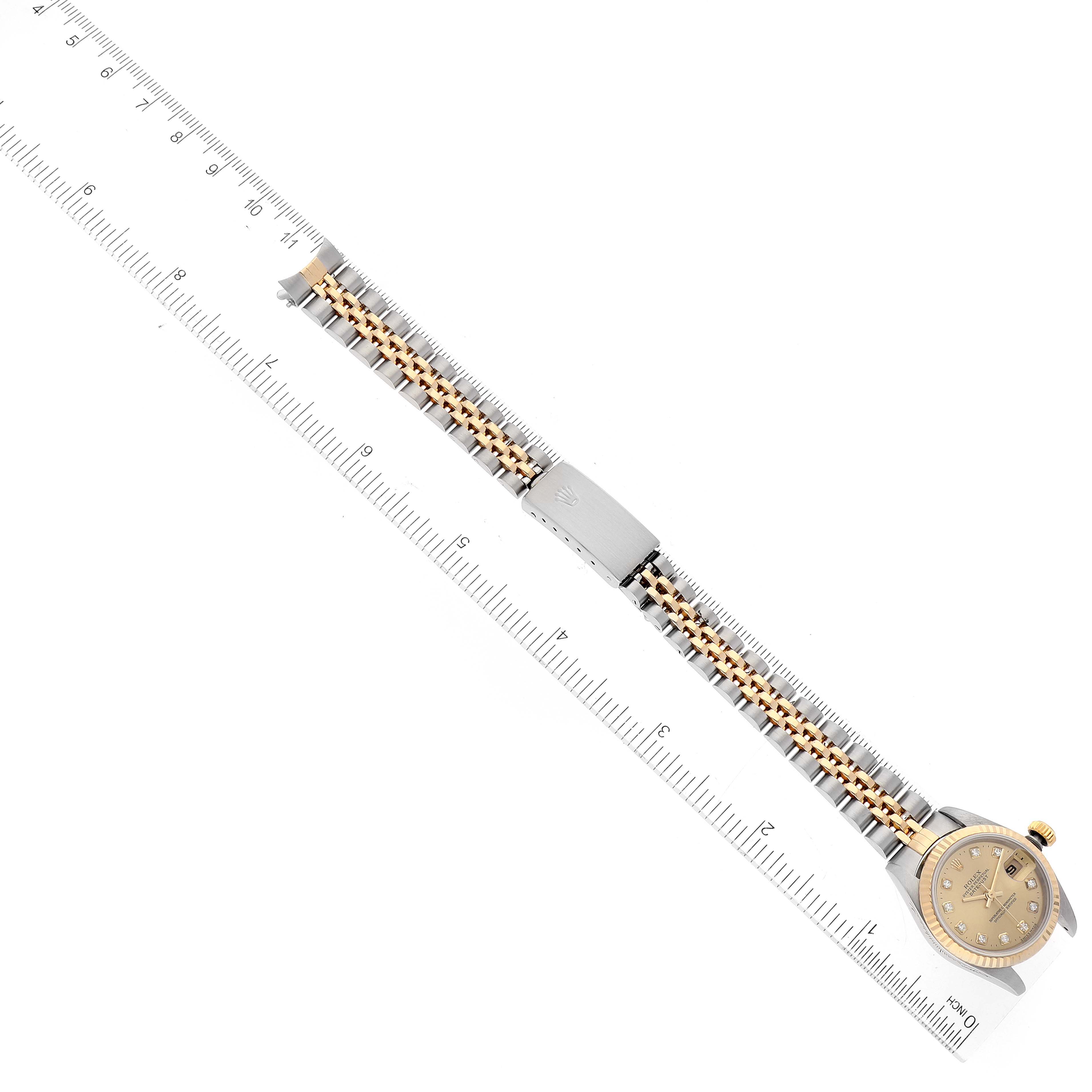 The image shows a Rolex Date 79173 Women's Steel and Gold (two tone) Champagne Dial 79173 Women's Steel and Gold (two tone) Champagne Dial model watch laid flat next to a ruler, highlighting the bracelet and the watch face.