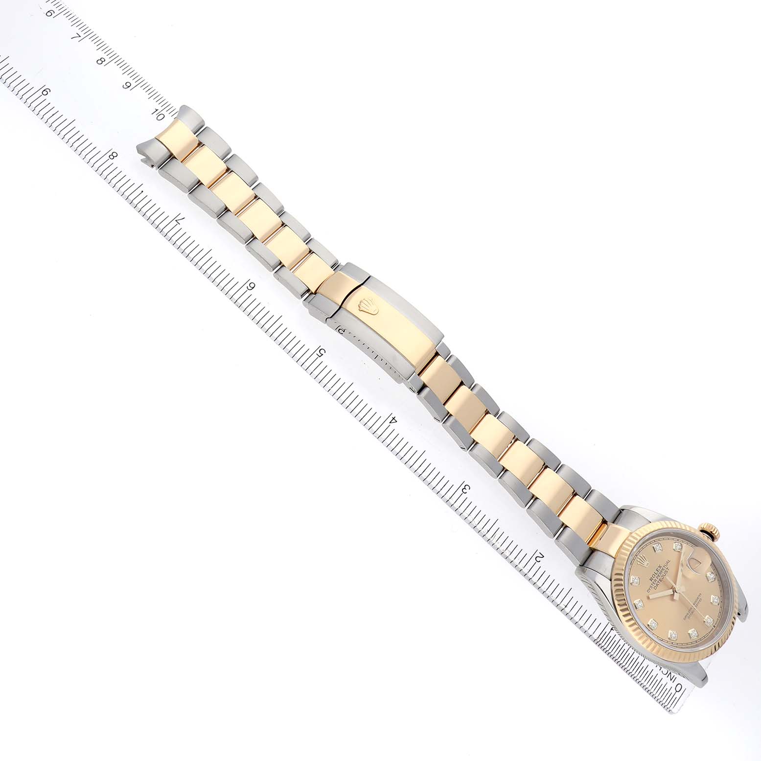 The Rolex Datejust 126233 Men
s Steel and Gold (two tone) Champagne Dial watch is shown from a top view, highlighting the dial, bracelet, and clasp next to a ruler.