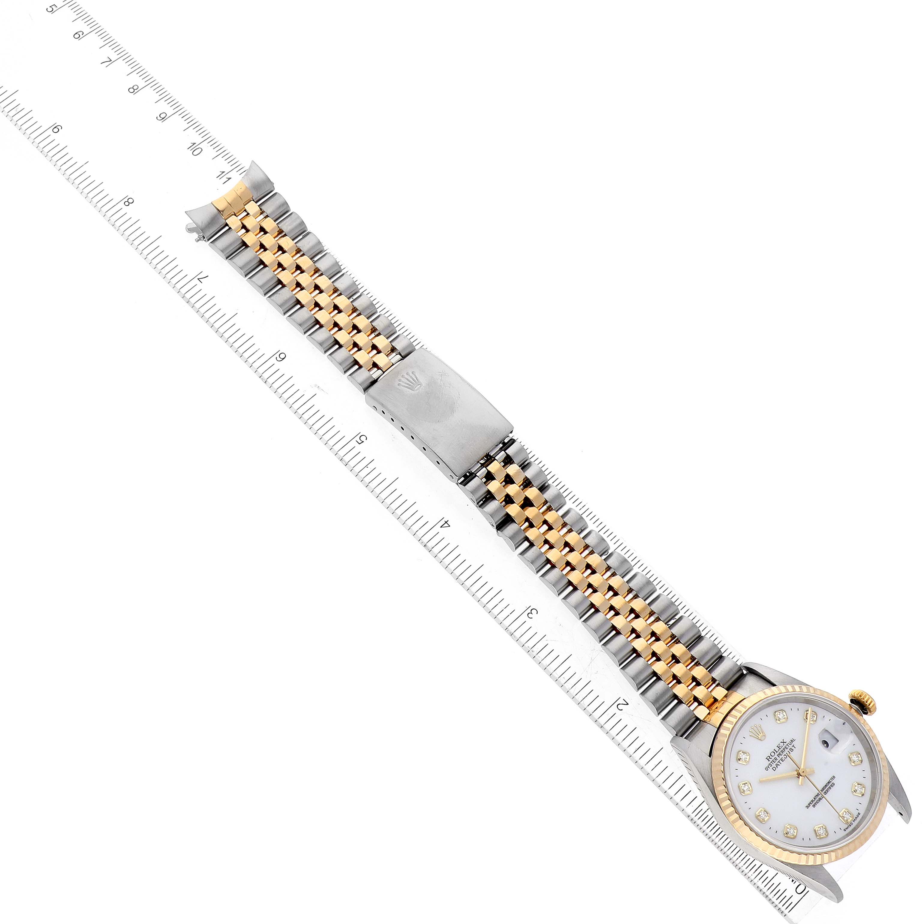 The image shows a top-down view of a Rolex Datejust 16233 Men's Steel and Gold (two tone) White Dial 16233 Men's Steel and Gold (two tone) White Dial watch with a two-tone bracelet and its deployment clasp alongside a ruler.