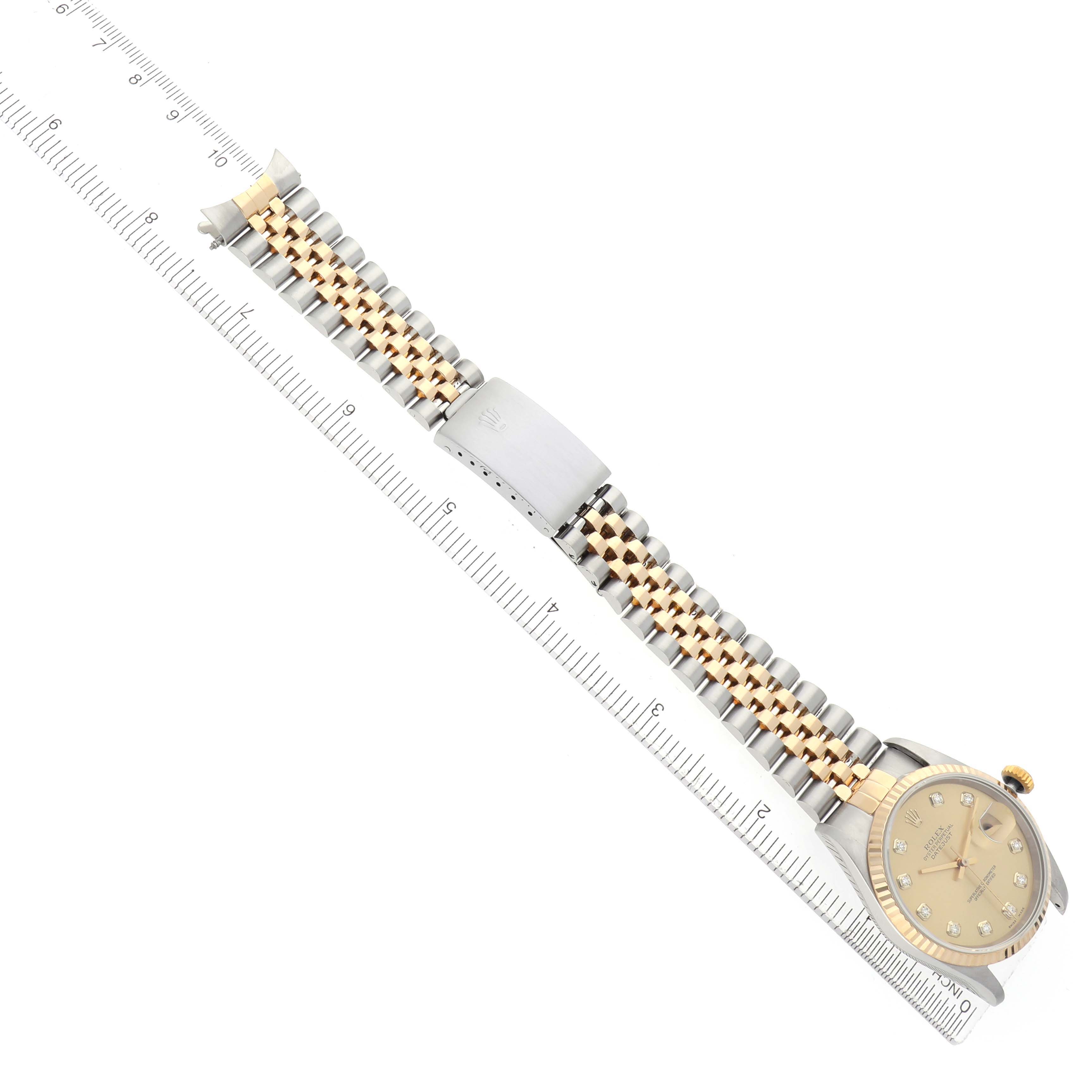 The Rolex Datejust 16233 Men
s Steel and Gold (two tone) Champagne Dial is shown at an angled top view, displaying the dial, bezel, bracelet, and clasp alongside a ruler.