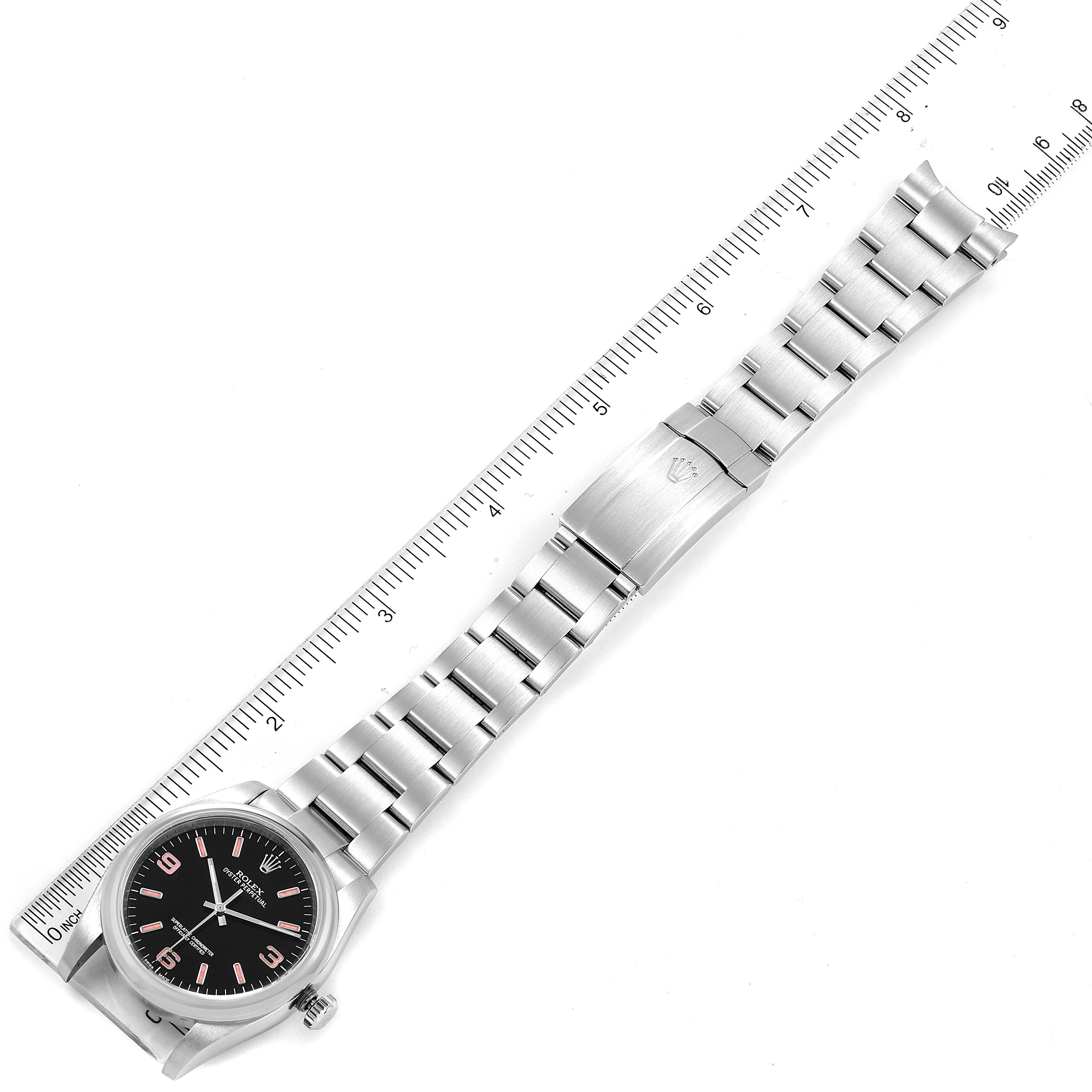 The image shows a top-down view of a Rolex Oyster Perpetual 116000 Men
s Stainless Steel Black Dial 116000 Men
s Stainless Steel Black Dial watch with its metal bracelet extended alongside a ruler.