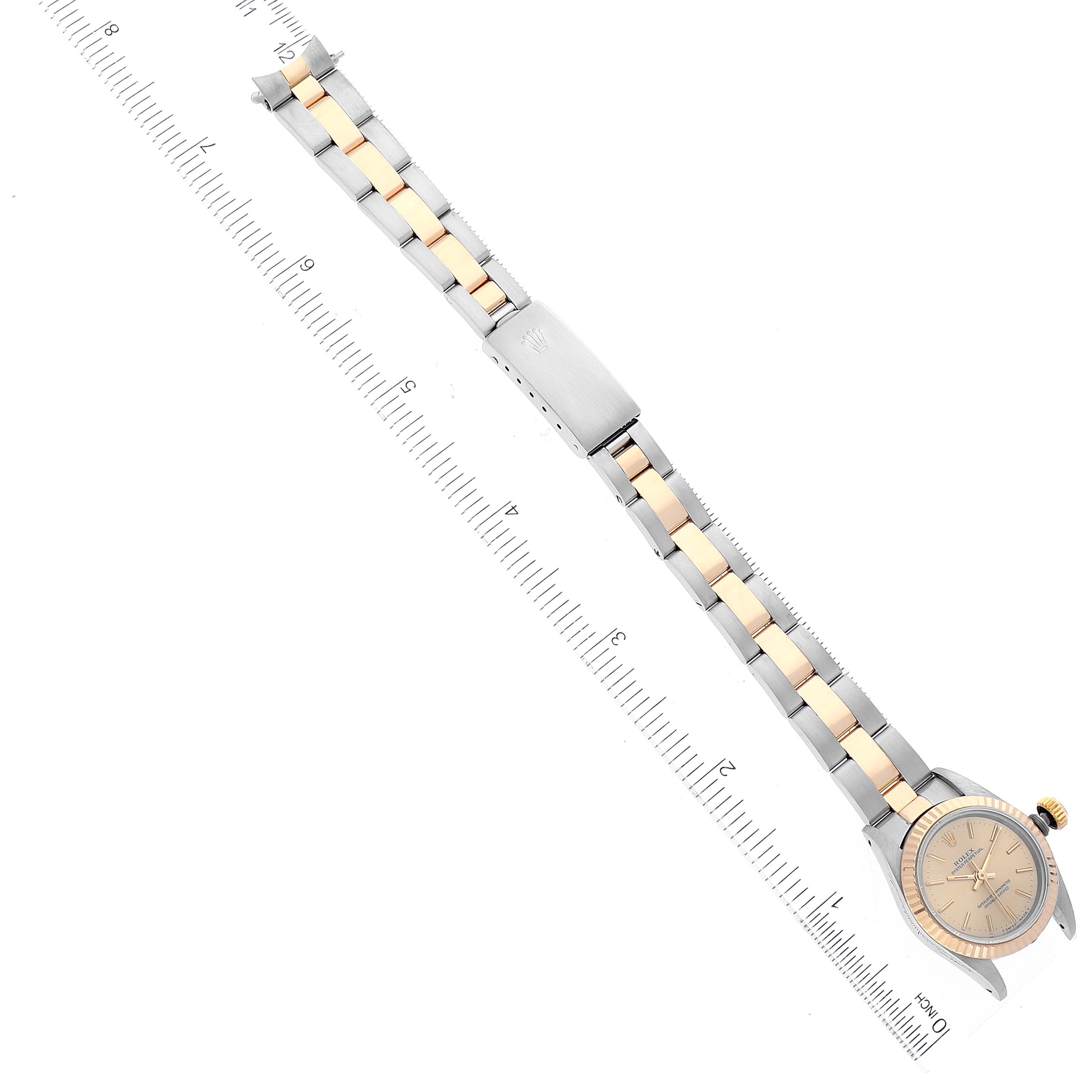 The image shows an overhead view of the Rolex Oyster Perpetual 67193 Women's Steel and Gold (two tone) Champagne Dial 67193 Women's Steel and Gold (two tone) Champagne Dial watch, displaying its full bracelet, clasp, and dial.