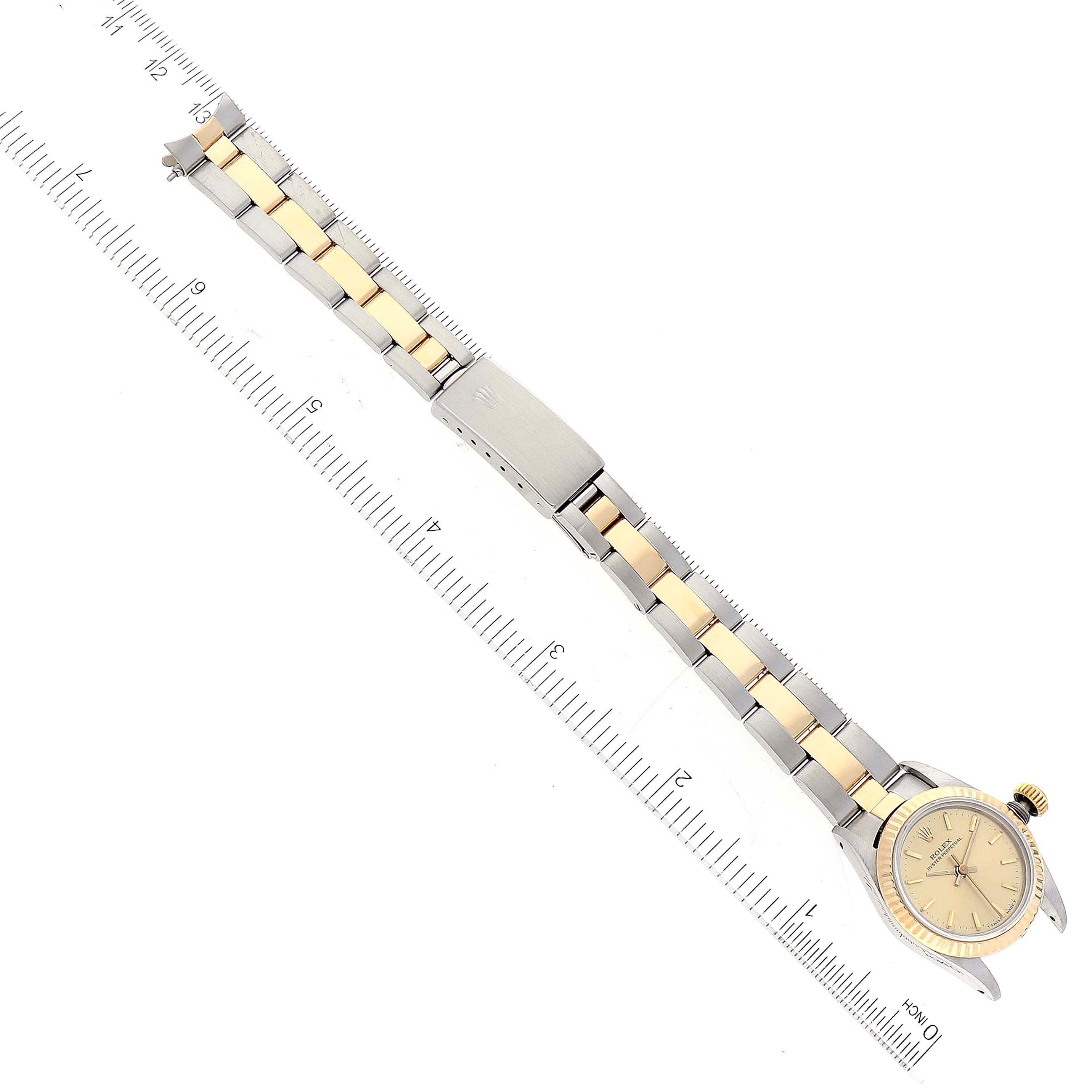 The image shows a top-down view of a Rolex Oyster Perpetual 67193 Women
s Steel and Gold (two tone) Champagne Dial 67193 Women
s Steel and Gold (two tone) Champagne Dial watch with a two-tone bracelet and measurement ruler.
