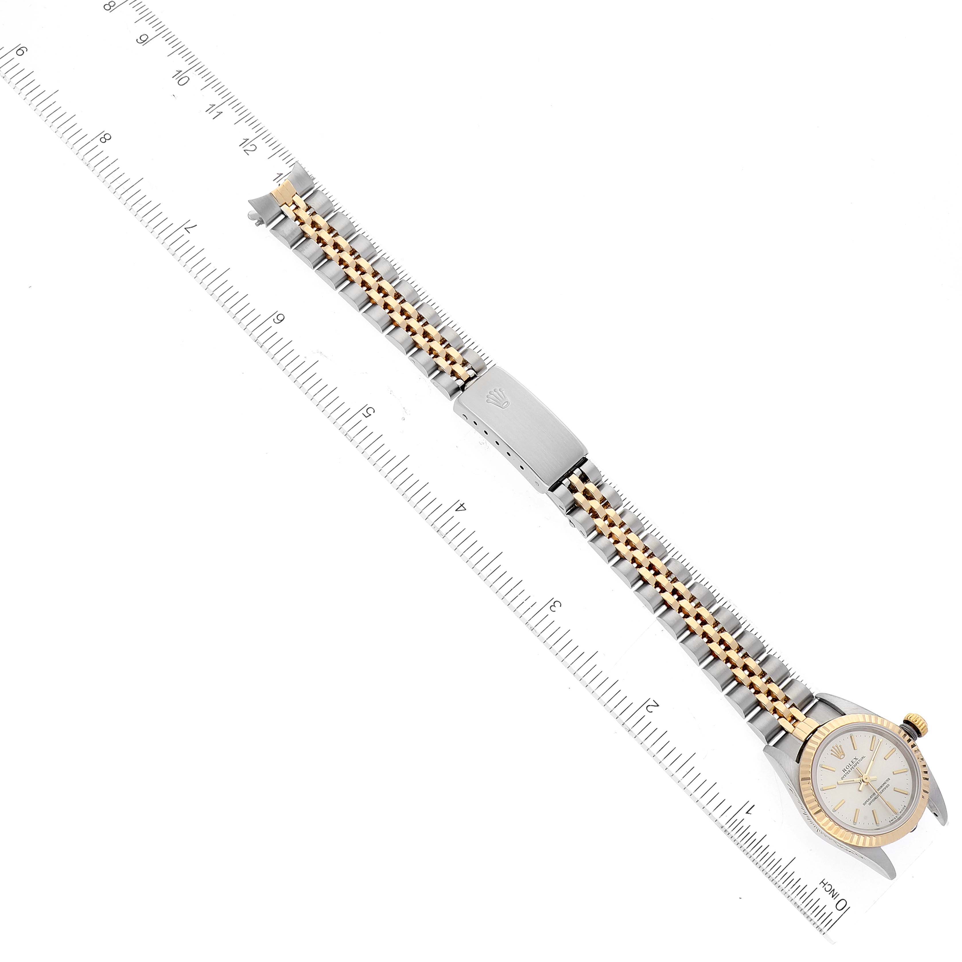 The image shows a Rolex Oyster Perpetual 76193 Women's Steel and Gold (two tone) Silver Dial 76193 Women's Steel and Gold (two tone) Silver Dial watch laid flat, displaying the face, bracelet, and clasp alongside a ruler for scale.