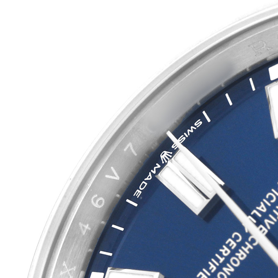 The image shows a close-up of the Rolex Oyster Perpetual 126000 Men's Stainless Steel Blue Dial's dial and bezel from an angled perspective, highlighting the blue dial.