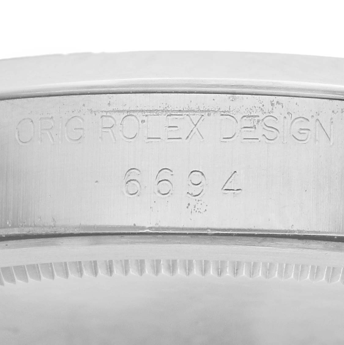 The image shows a close-up of the side of a Rolex Vintage Collection 6694 Men
s Stainless Steel Black Dial watch case with engraved text and its reference number.