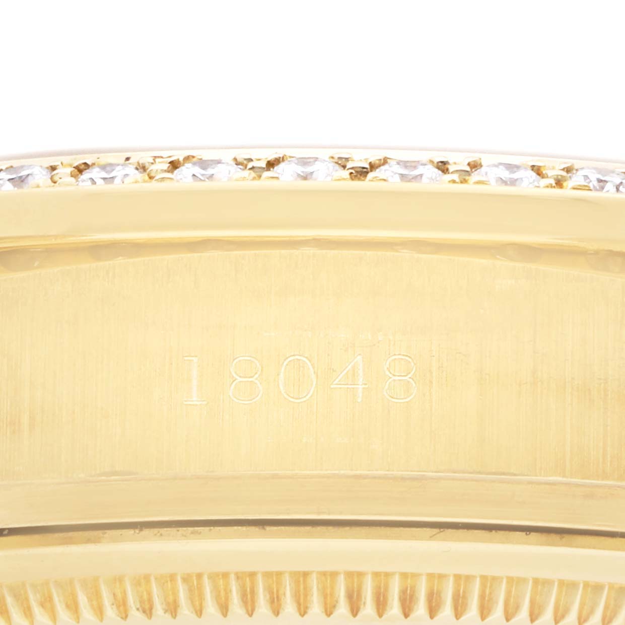 The image shows a close-up of the engraved side of a Rolex President 18048 Men
s Yellow Gold Champagne Dial model watch, featuring the number "18048" and parts of the bezel.