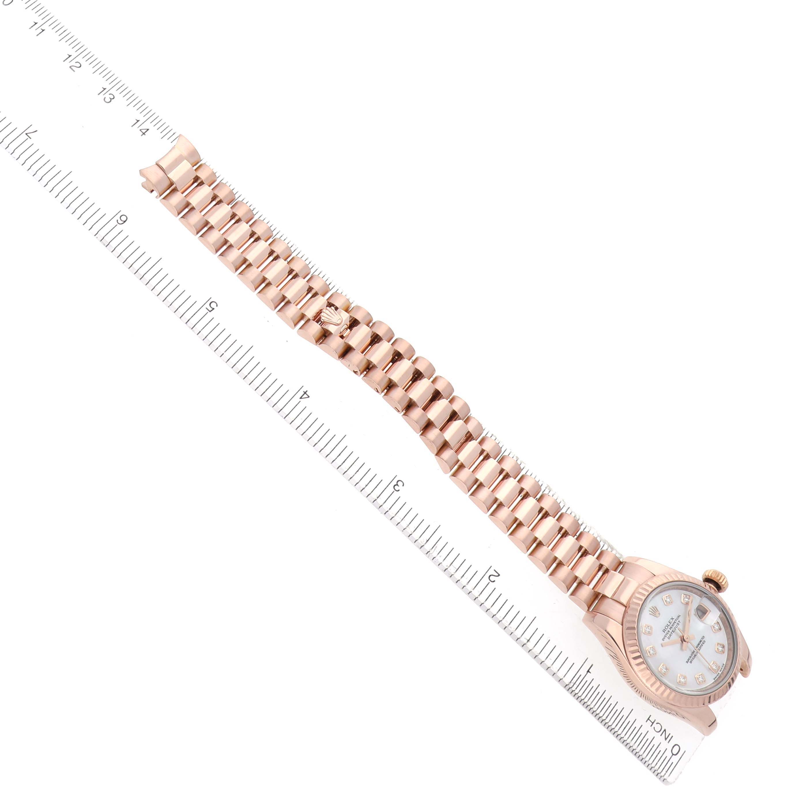 The image shows the Rolex President 179175 Women
s Rose Gold Mother of Pearl Dial model watch at a top-down angle, highlighting the bracelet and face with a ruler for scale.