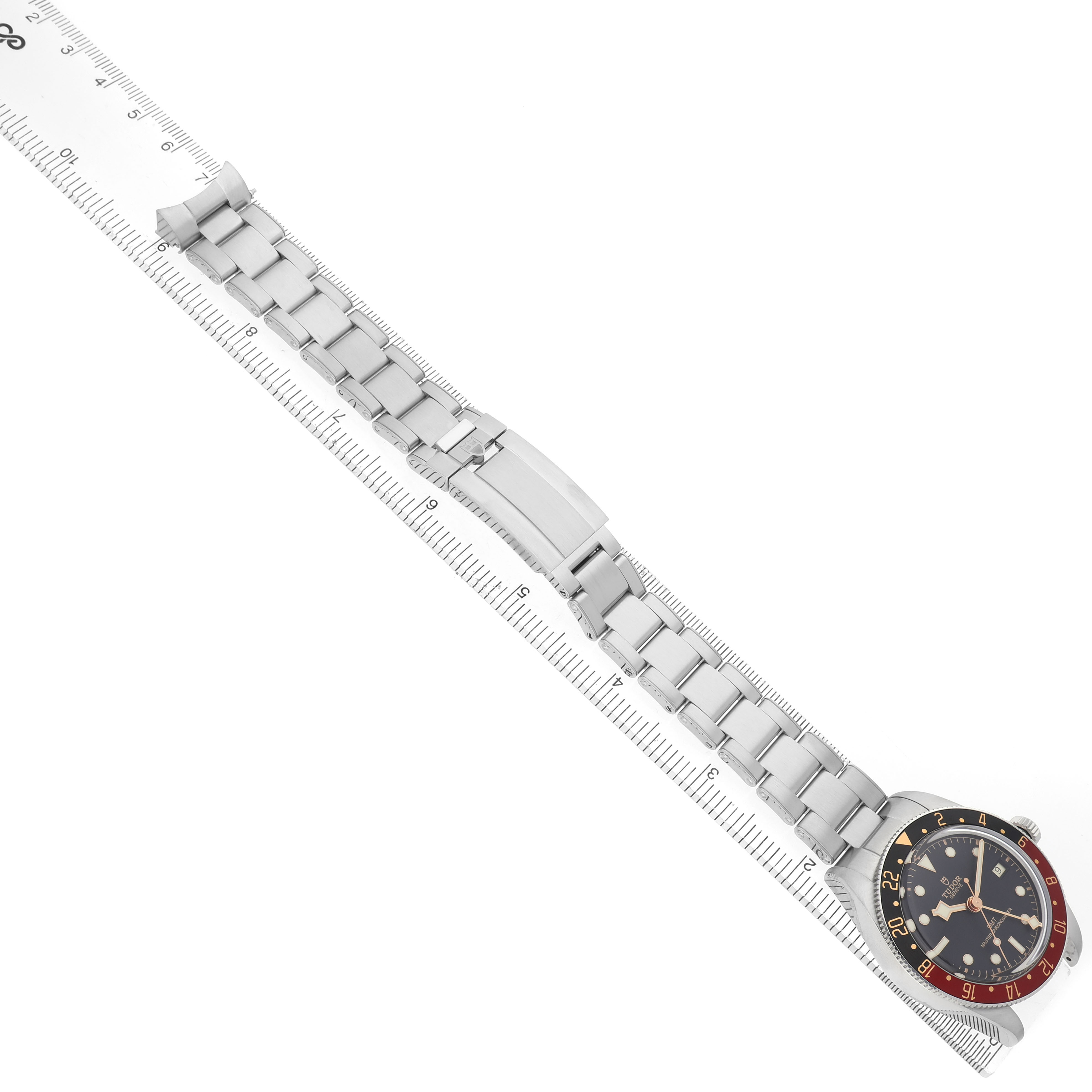 The Tudor Heritage Black Bay 7939G Men's Stainless Steel Black Dial watch is shown from a top-down angle, featuring its bracelet, clasp, and watch face.