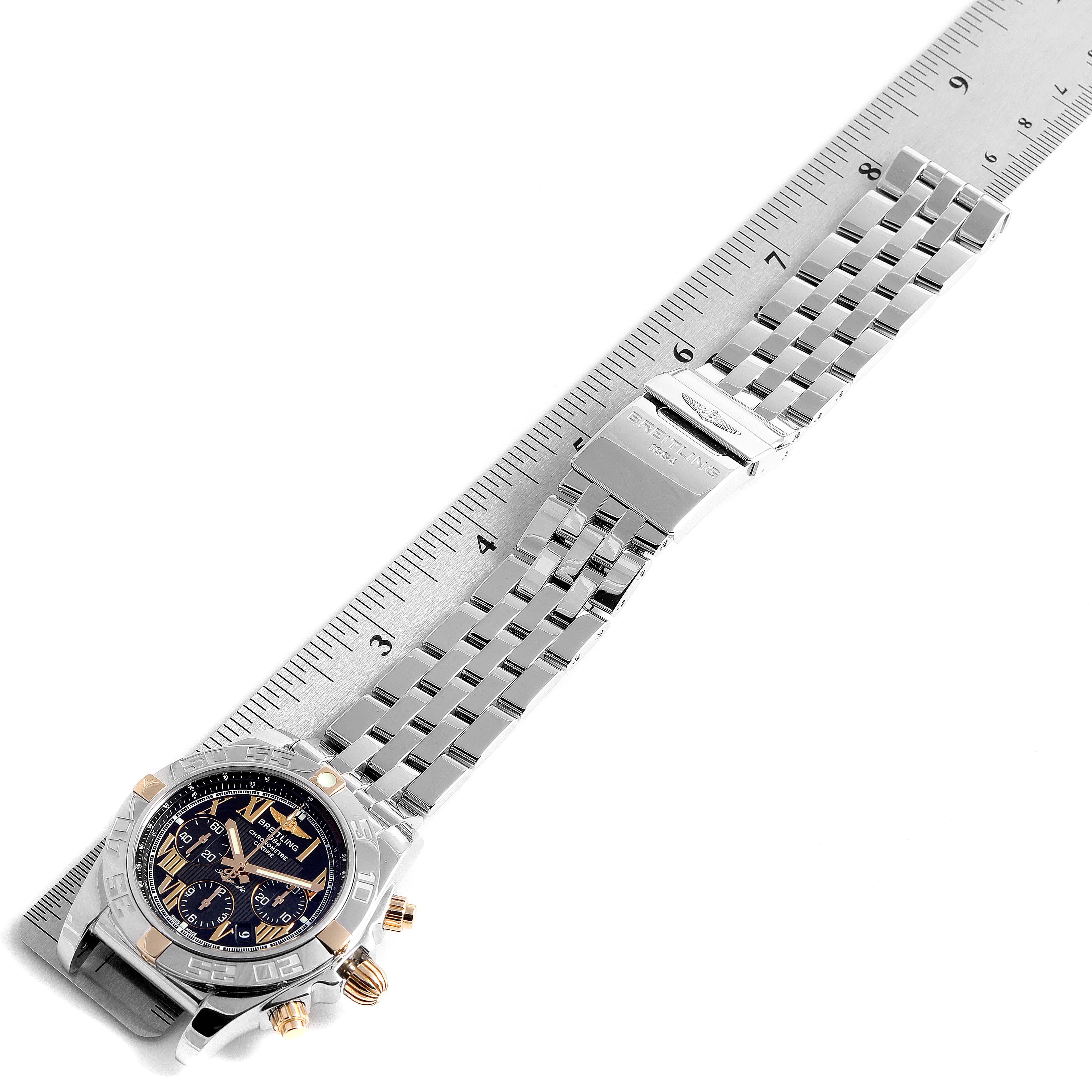 The image shows an overhead view of a Breitling Chronomat IB0110 Men's Stainless Steel Black Dial IB0110 Men's Stainless Steel Black Dial watch with a focus on the face and bracelet, placed alongside a ruler.