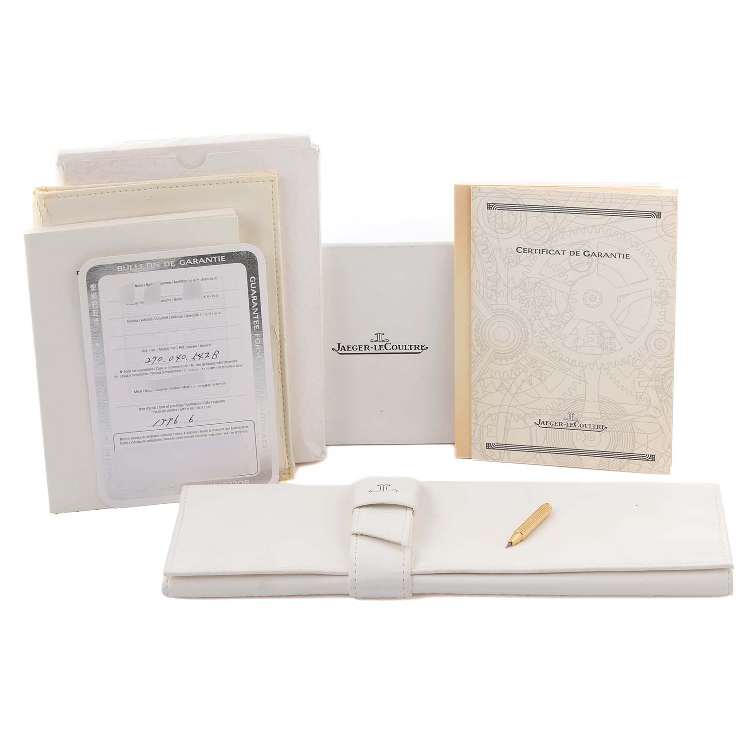 This image shows accessories for a Jaeger-LeCoultre Reverso, including manuals, a warranty card, and a white leather case with a pen.