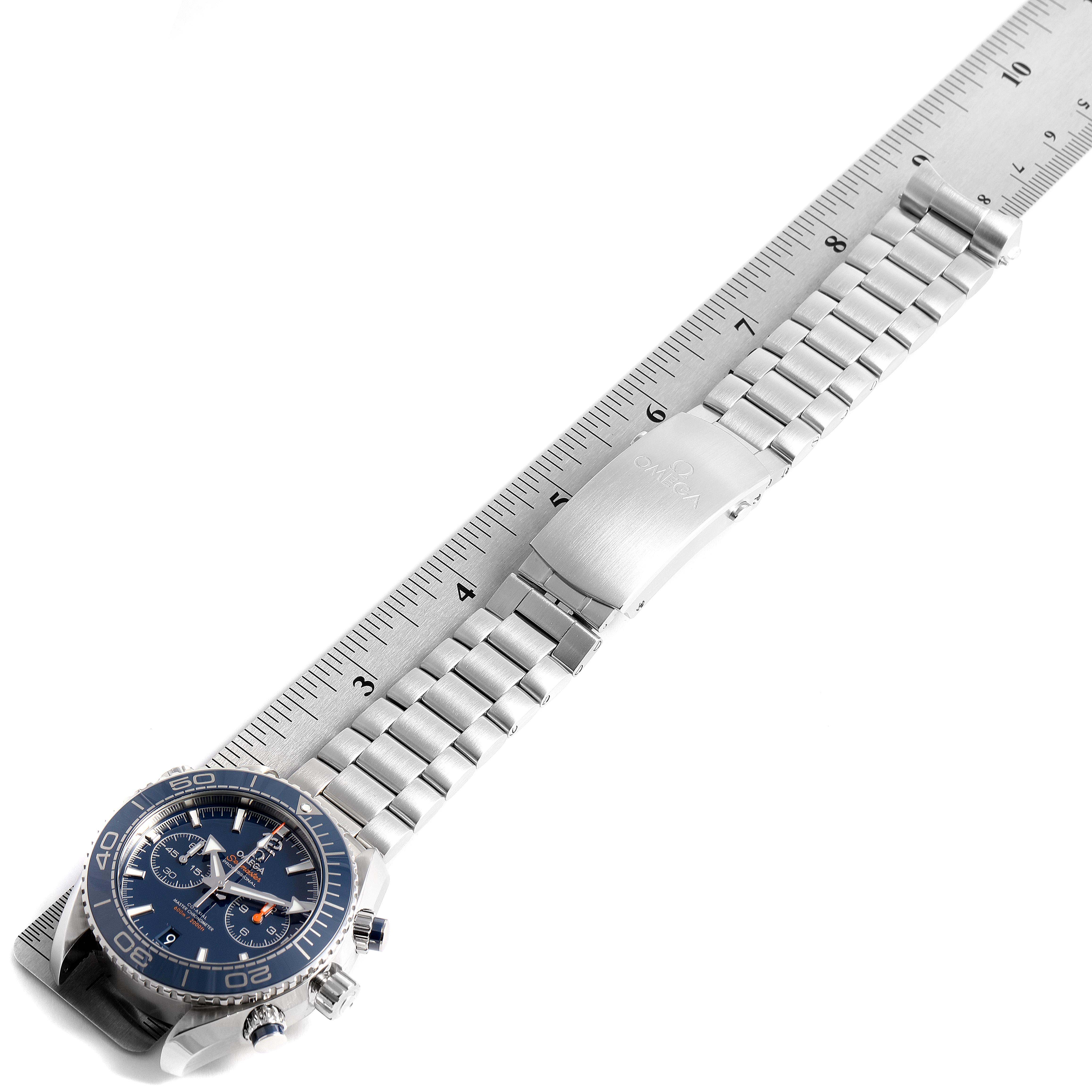 The image shows an Omega Planet Ocean 215.30.46.51.03.001 Men
s Stainless Steel Blue Dial 215.30.46.51.03.001 Men
s Stainless Steel Blue Dial watch with a metal bracelet and clasp, placed against a measuring ruler, viewed from a slightly diagonal top angle.
