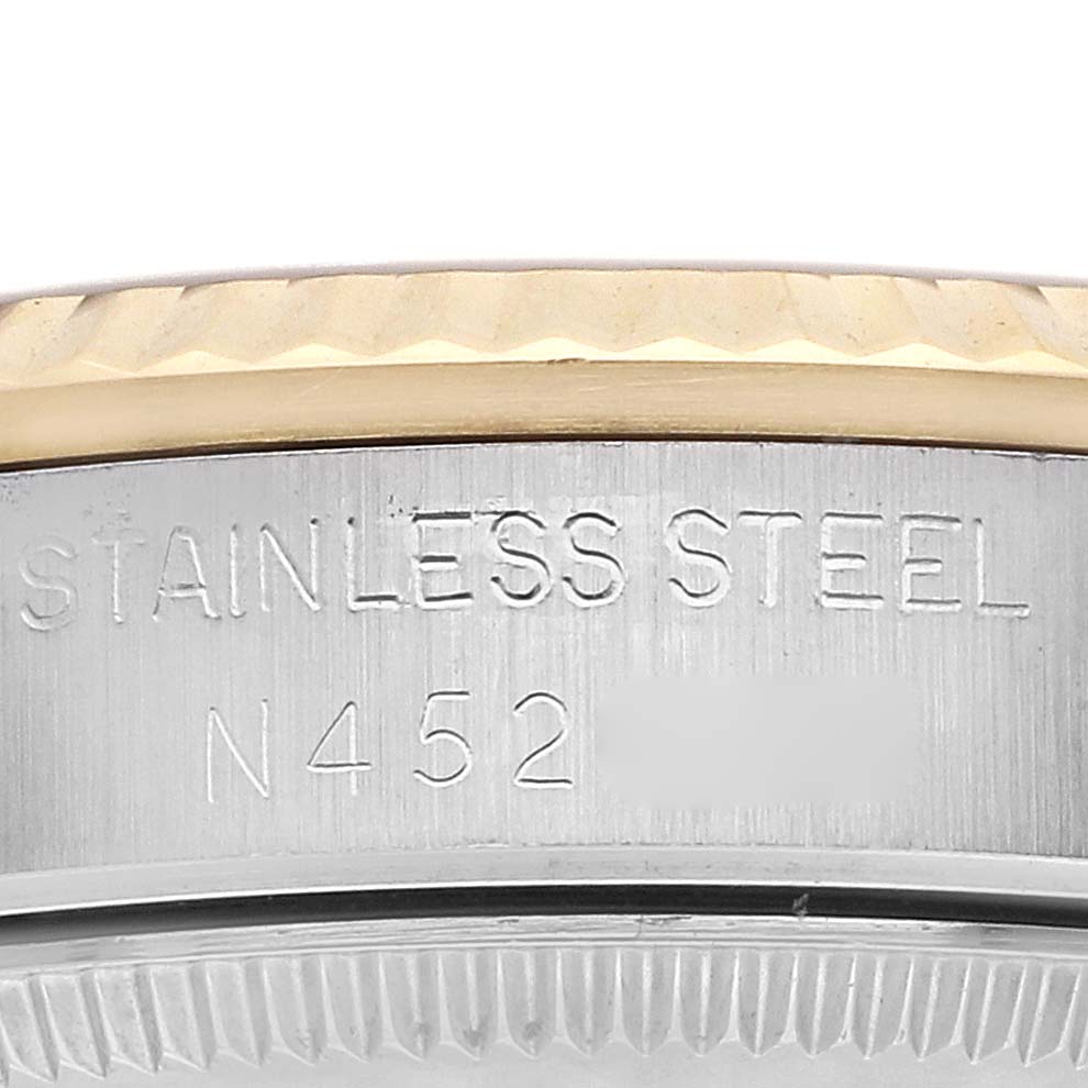 The image shows a close-up of a Rolex Mid-Size 68273 Women
s Steel and Gold (two tone) Champagne Dial watch
s stainless steel side with engraved text.