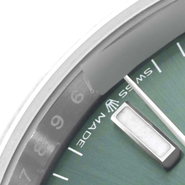 The image shows a close-up of the dial and bezel of a Rolex Datejust 126200 Men's Stainless Steel Green Dial 126200 Men's Stainless Steel Green Dial watch, focusing on the edge and hour markers.
