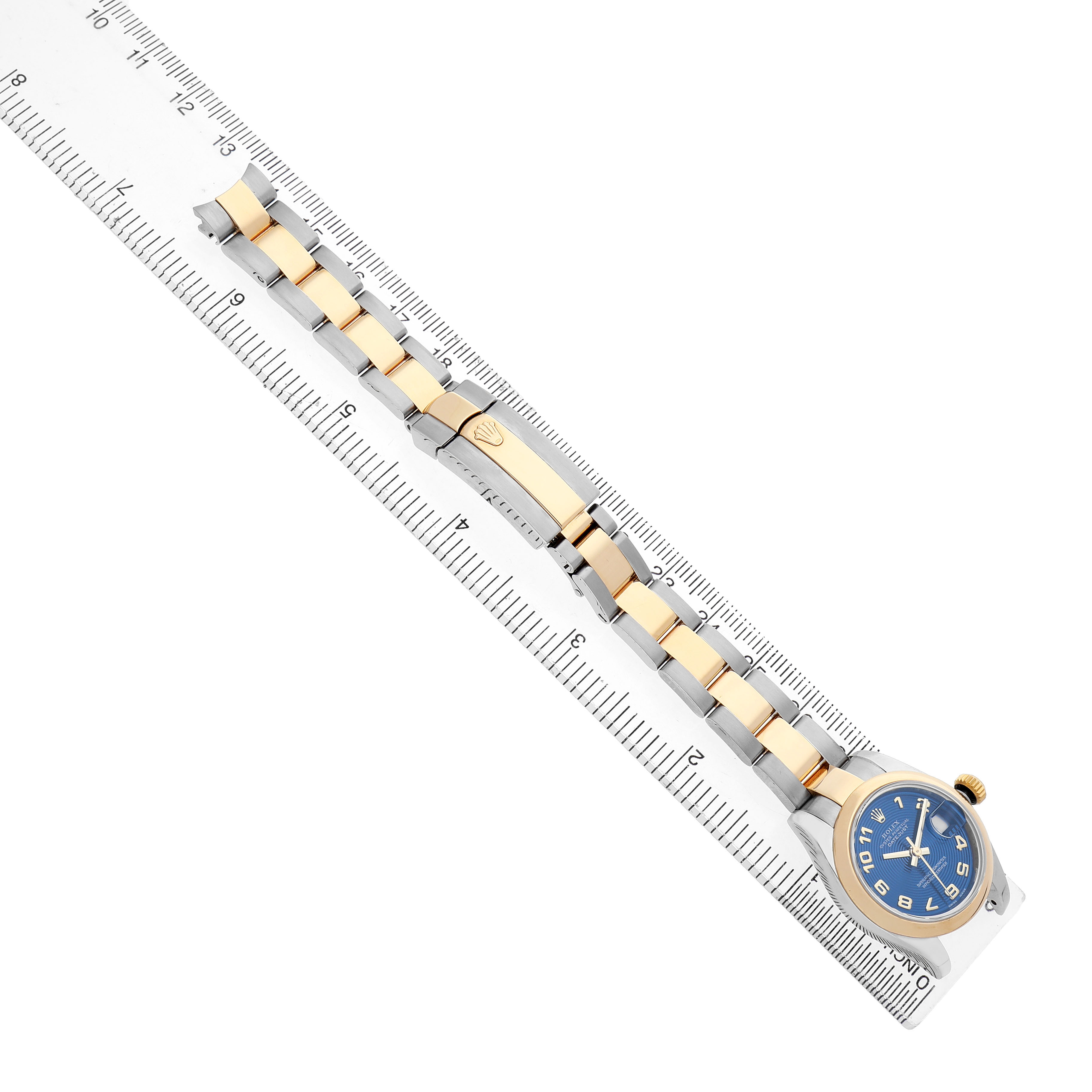 The image shows a Rolex Datejust 179163 Women's Steel and Gold (two tone) Blue Dial watch laid flat next to a ruler, highlighting its bracelet and face from a top-down angle.