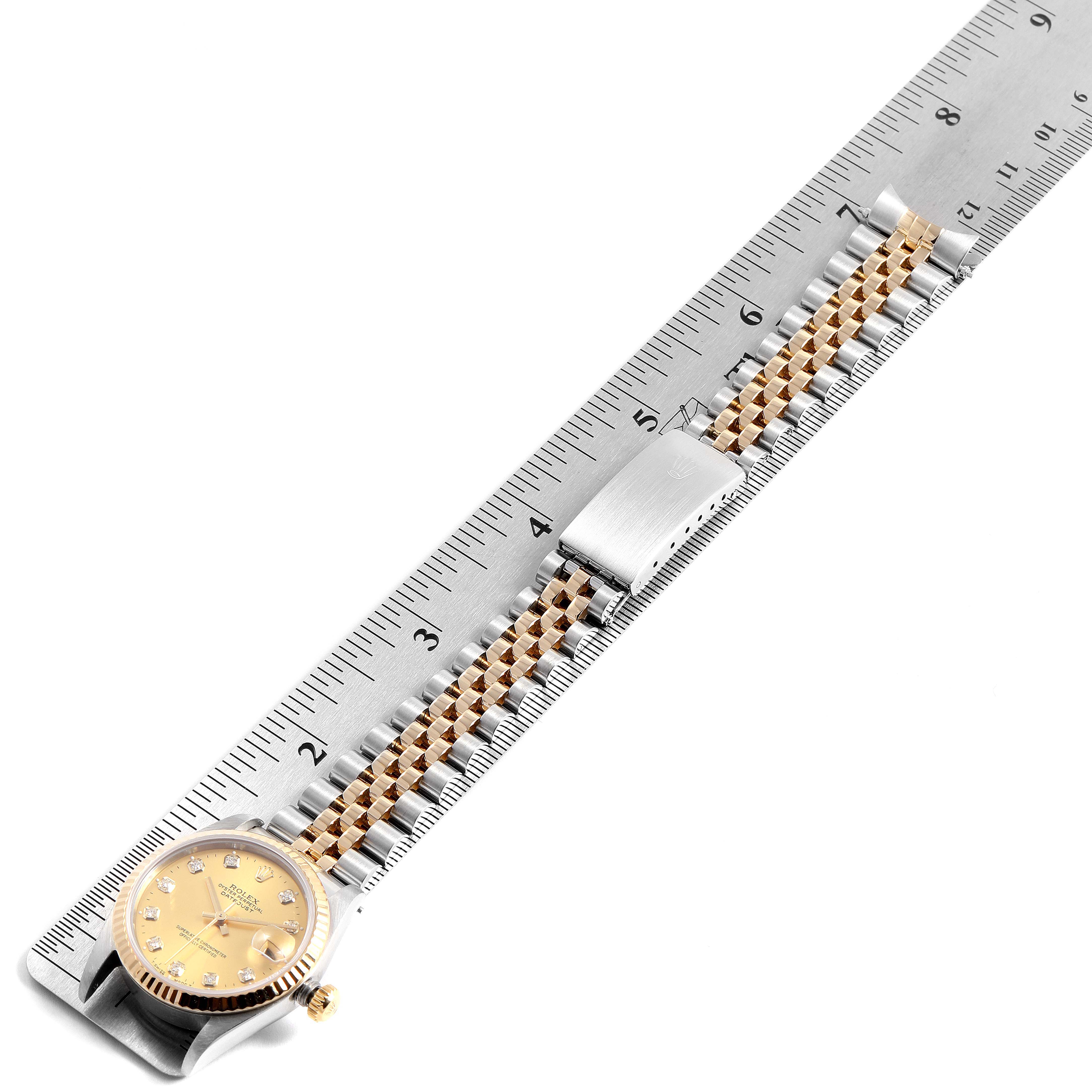 The image shows a Mid-Size Rolex watch laid flat next to a ruler, displaying its face and bracelet.