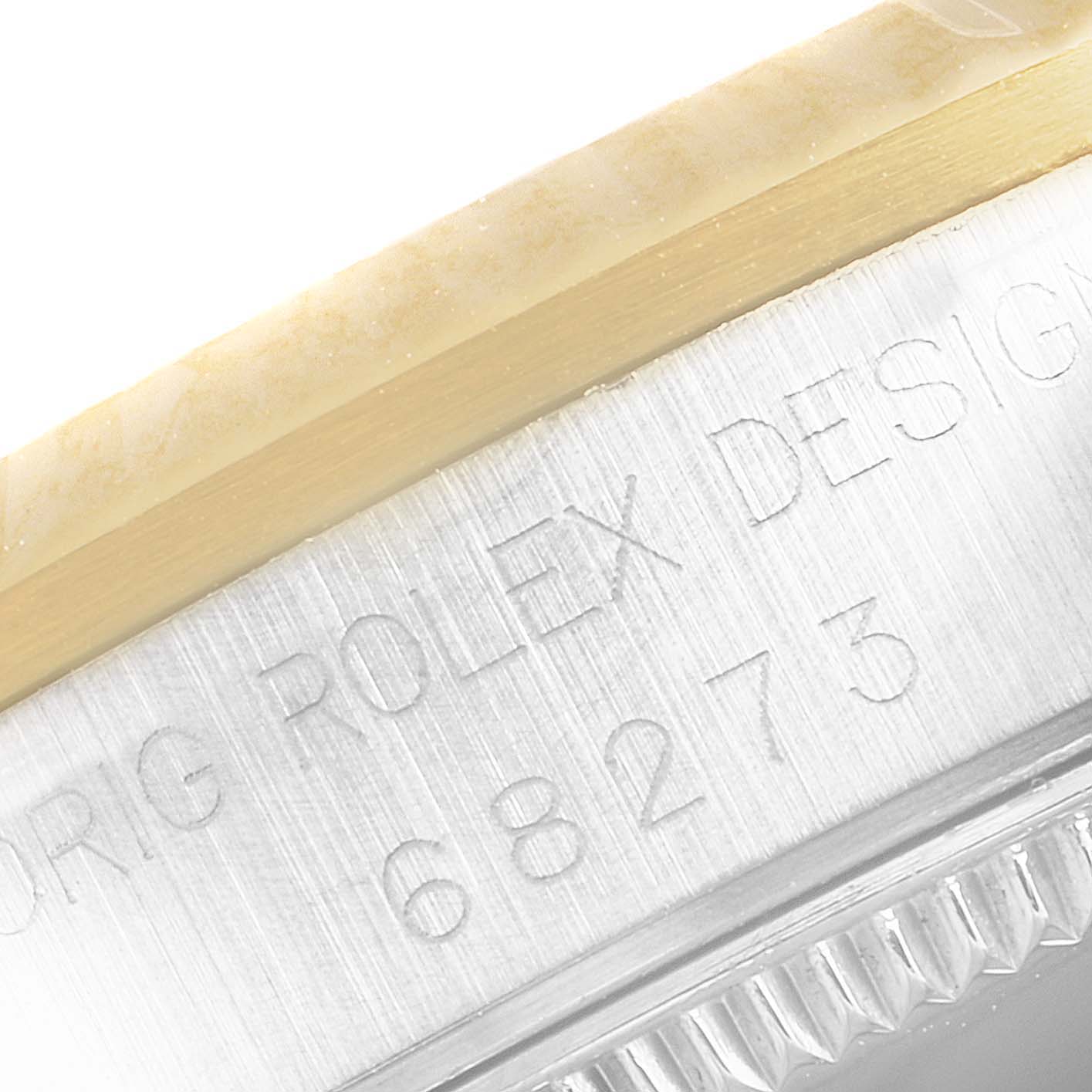 The image shows a close-up of the side of a Rolex Mid-Size 68273 Women
s Steel and Gold (two tone) Champagne Dial 68273 Women
s Steel and Gold (two tone) Champagne Dial watch case, featuring part of the model number 68273 and text engraved on the metal case.