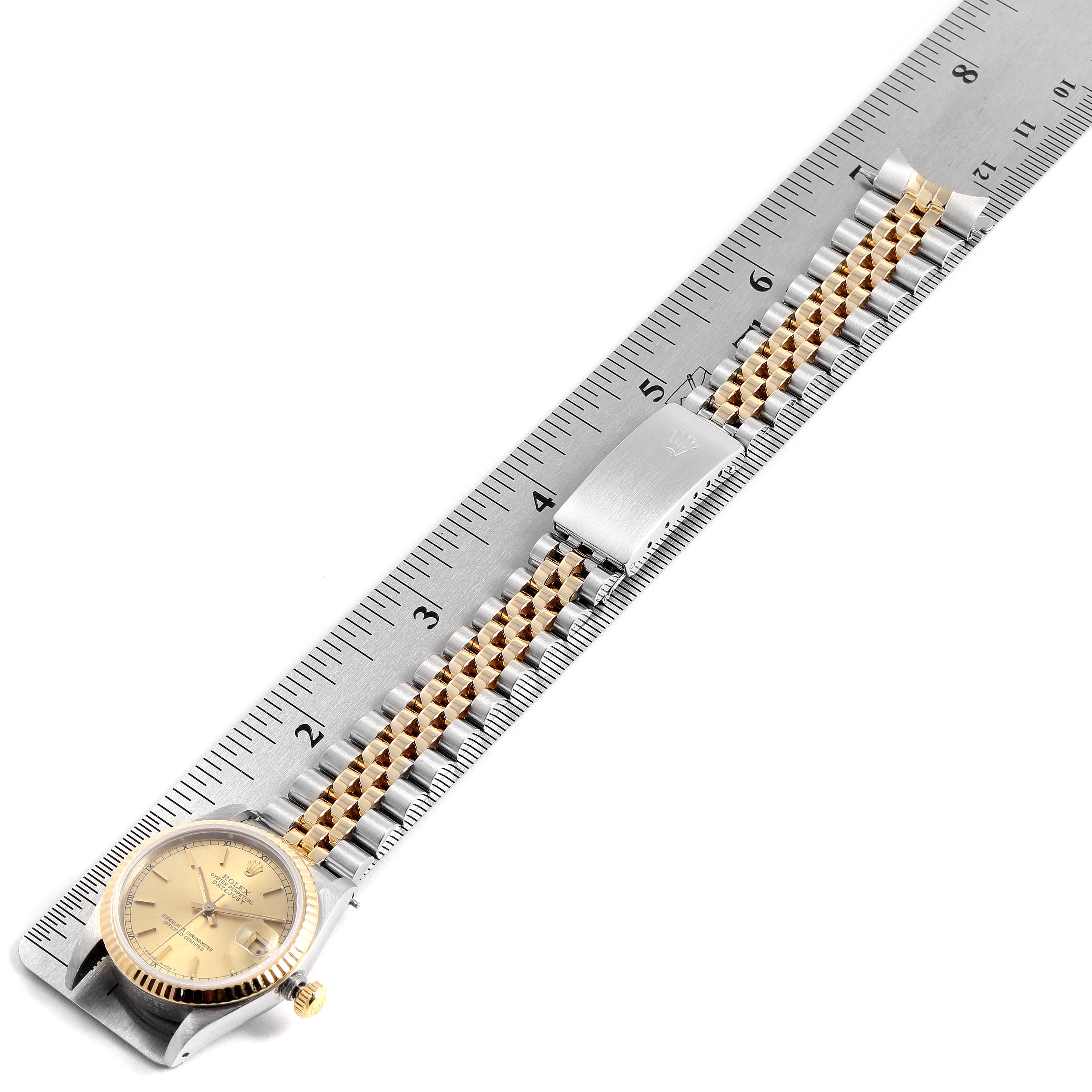 The Rolex Mid-Size 68273 Women
s Steel and Gold (two tone) Champagne Dial 68273 Women
s Steel and Gold (two tone) Champagne Dial watch is shown flat with a ruler, highlighting its gold-tone dial, case, and two-tone bracelet.