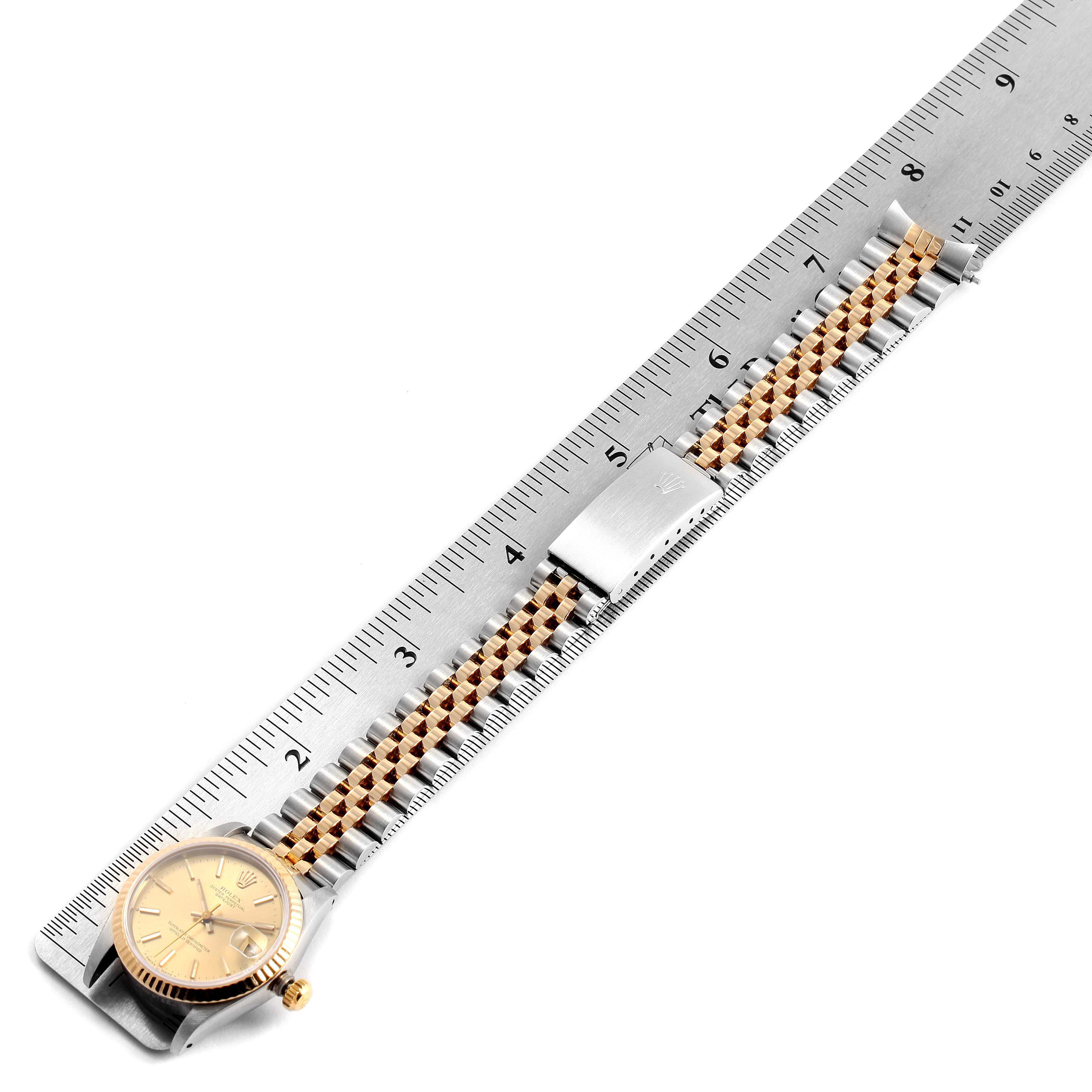 The Rolex Mid-Size 68273 Women's Steel and Gold (two tone) Champagne Dial 68273 Women's Steel and Gold (two tone) Champagne Dial watch is shown in a top-down angle with its face, bracelet, and clasp visible next to a ruler.