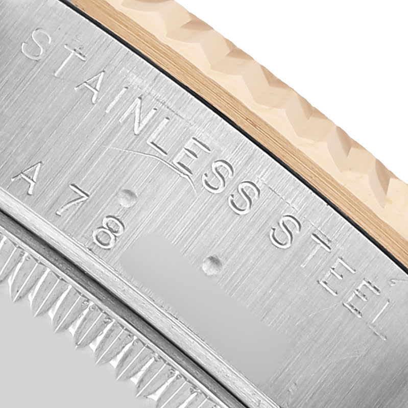 The image shows a close-up of the Rolex Datejust 78273 Women's Steel and Gold (two tone) Red Dial's stainless steel outer edge with engraved text.