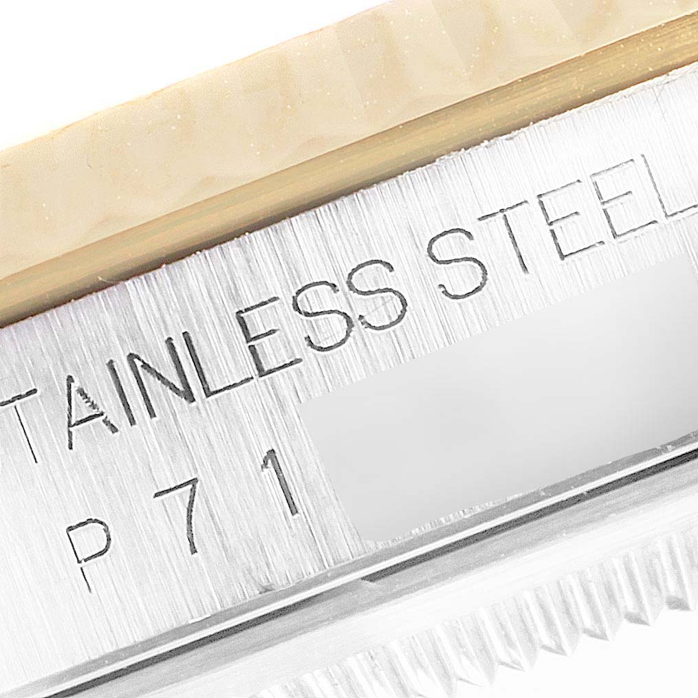 This image shows a close-up angle of the "STAINLESS STEEL" engraving and the fluted bezel of a Rolex Datejust 16233 Men's Steel and Gold (two tone) Champagne Dial 16233 Men's Steel and Gold (two tone) Champagne Dial watch.