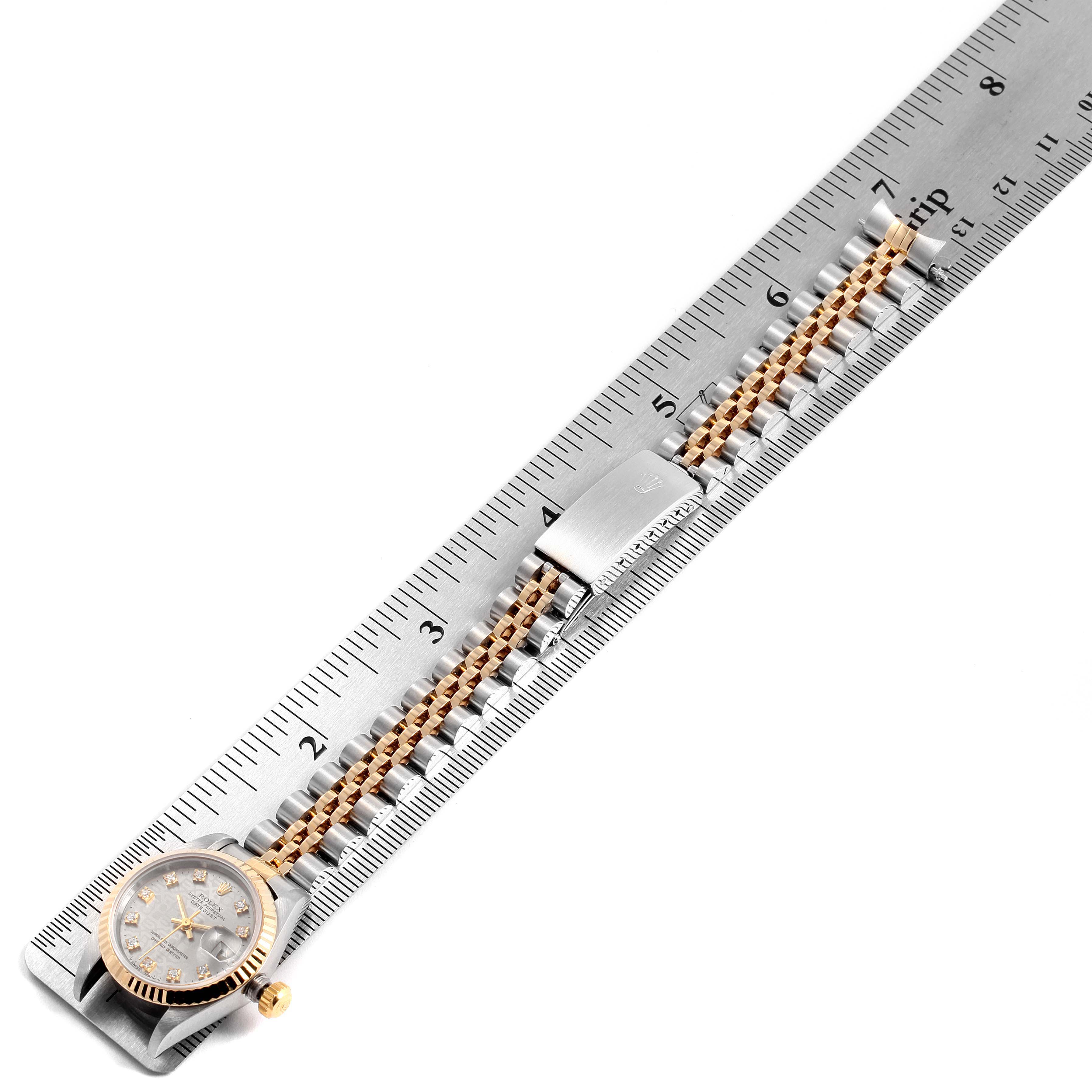 The Rolex Datejust 69173 Women's Steel and Gold (two tone) Silver Dial 69173 Women's Steel and Gold (two tone) Silver Dial watch is positioned next to a ruler, displaying the watch's face, bezel, and part of its bracelet.