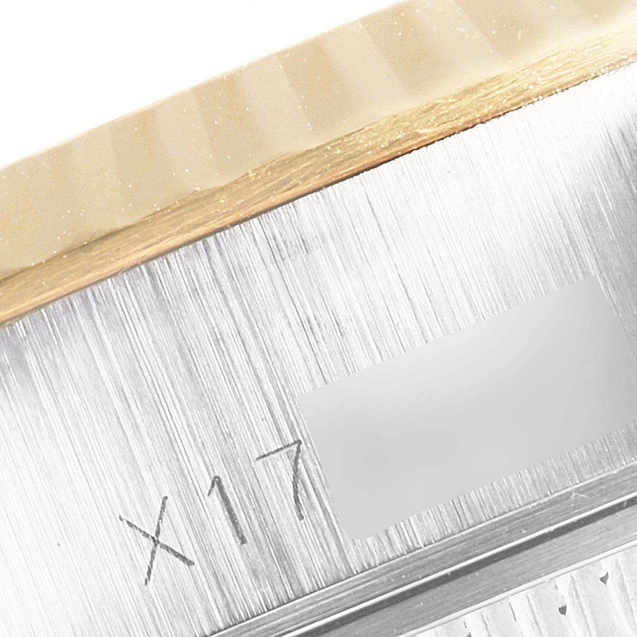 This close-up image of a Datejust model by Rolex shows a portion of the bezel and the engraved serial number on the case.