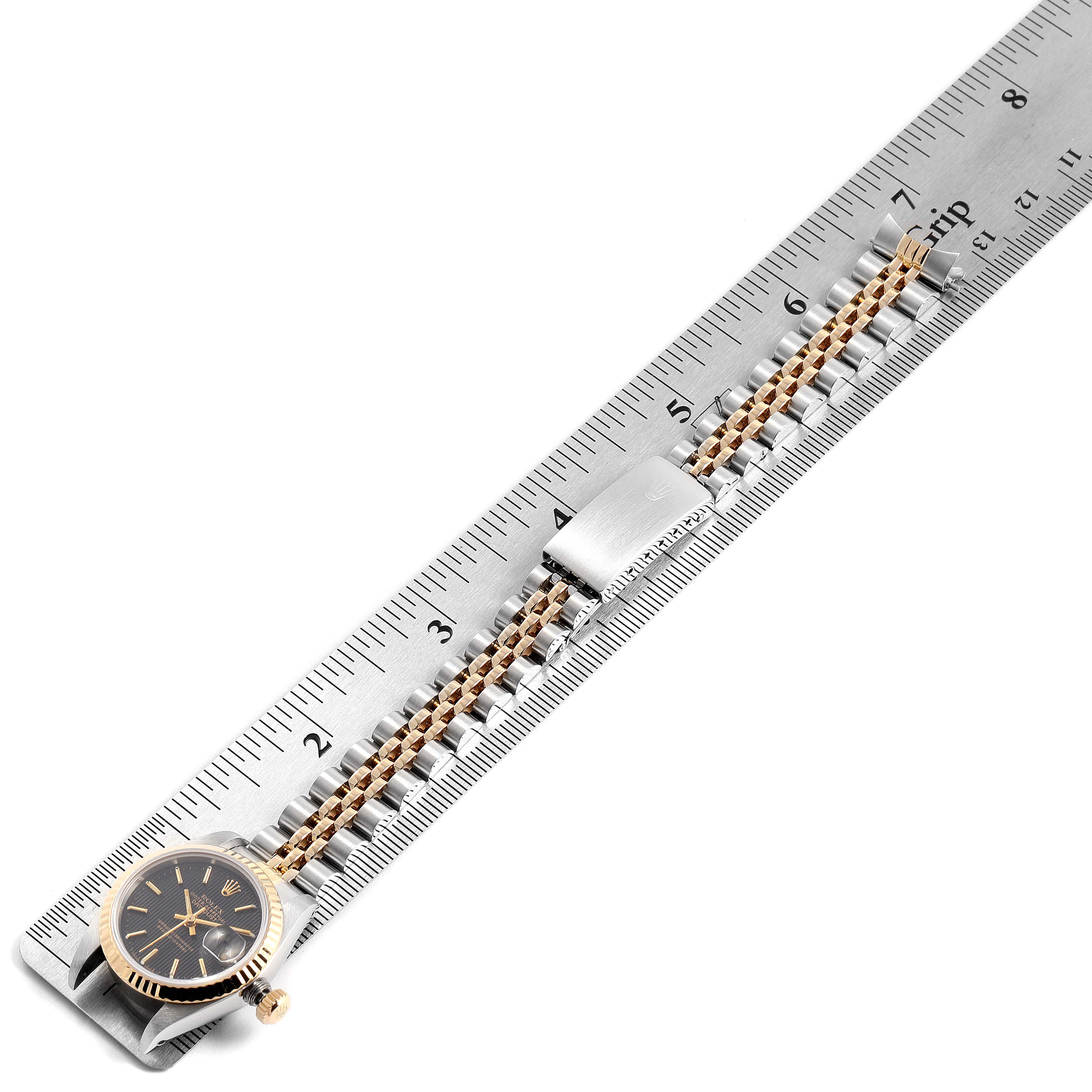 The image shows the face and bracelet of a Rolex Datejust 69173 Women
s Steel and Gold (two tone) Black Dial 69173 Women
s Steel and Gold (two tone) Black Dial watch placed alongside a ruler for size reference.