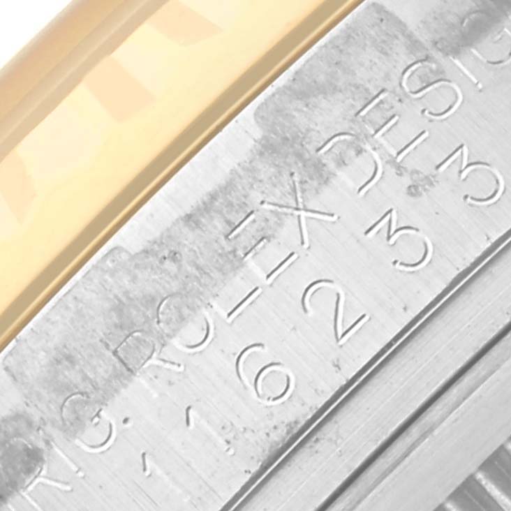 The image shows an extreme close-up of the edge of a Rolex Datejust 116233 Men
s Steel and Gold (two tone) Champagne Dial 116233 Men
s Steel and Gold (two tone) Champagne Dial watch, focusing on the engraved bezel and gold trim.