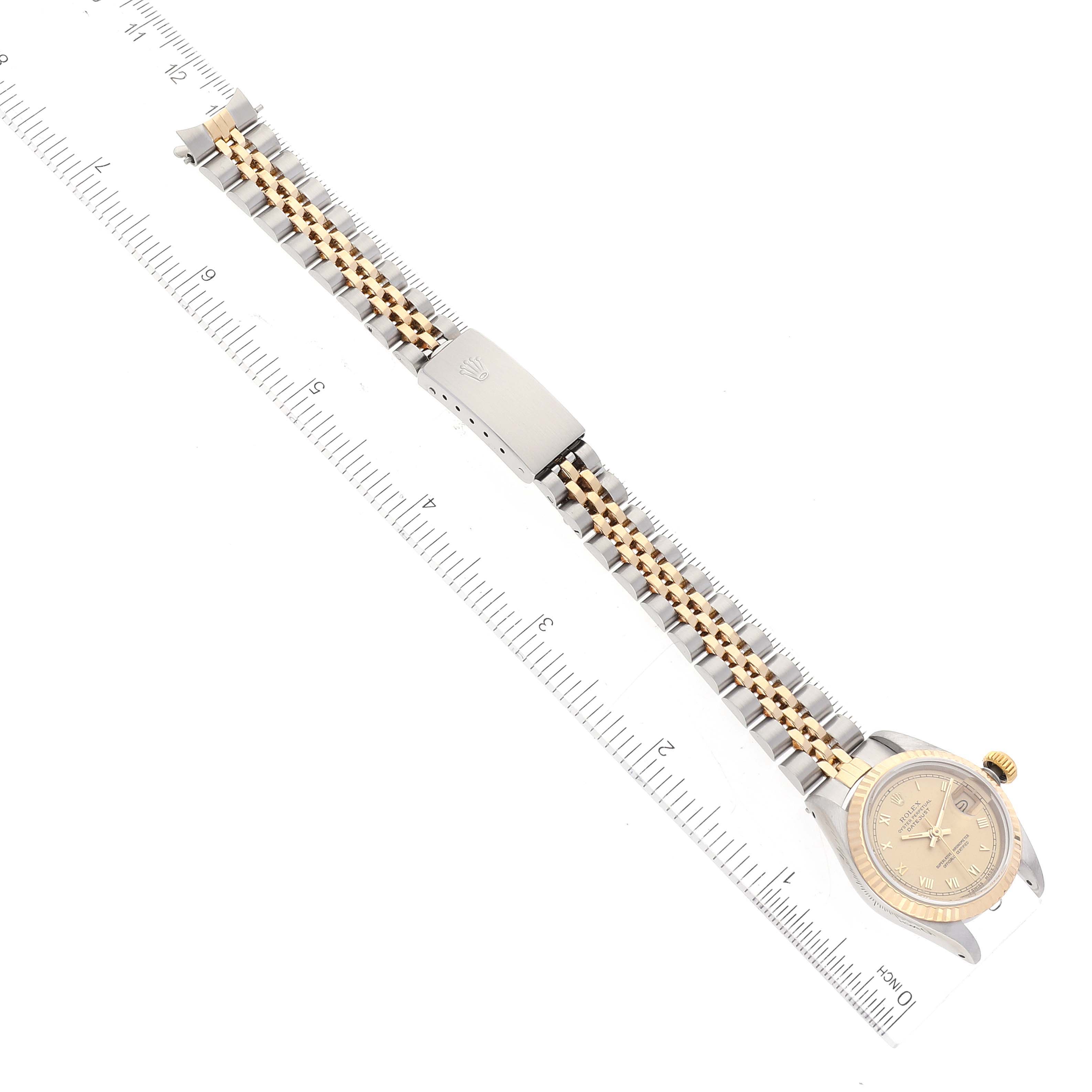 This image shows the Rolex Datejust 69173 Women's Steel and Gold (two tone) Champagne Dial 69173 Women's Steel and Gold (two tone) Champagne Dial watch laid flat next to a ruler, displaying its bracelet, clasp, and dial from an overhead angle.