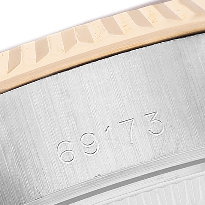 The image shows a close-up of the Rolex Datejust 69173 Women's Steel and Gold (two tone) Silver Dial model's engraved watch case number and a portion of the bezel.