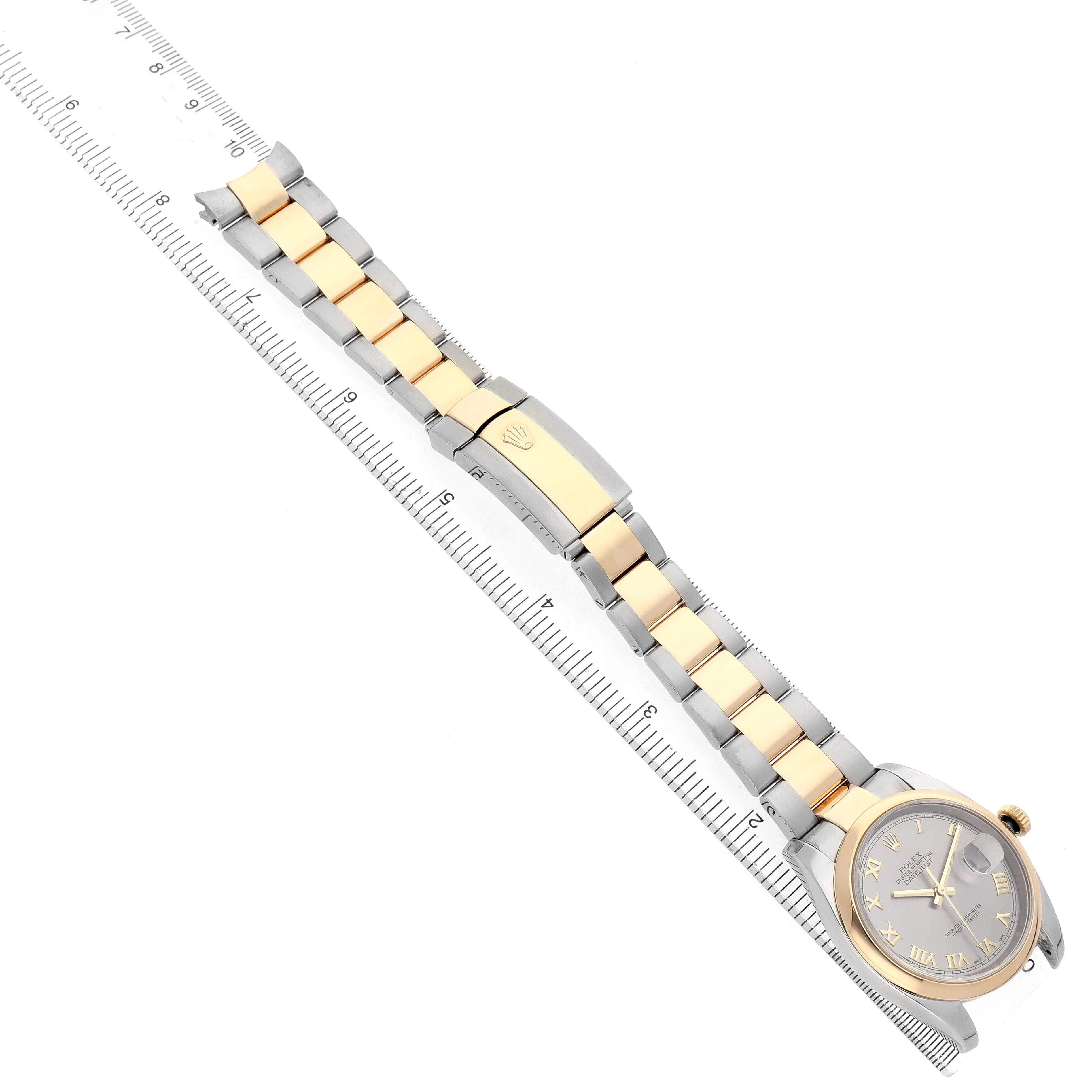 The Rolex Datejust 116203 Men's Steel and Gold (two tone) Grey Dial is shown from above, highlighting its bracelet, clasp, and dial alongside a ruler for scale.