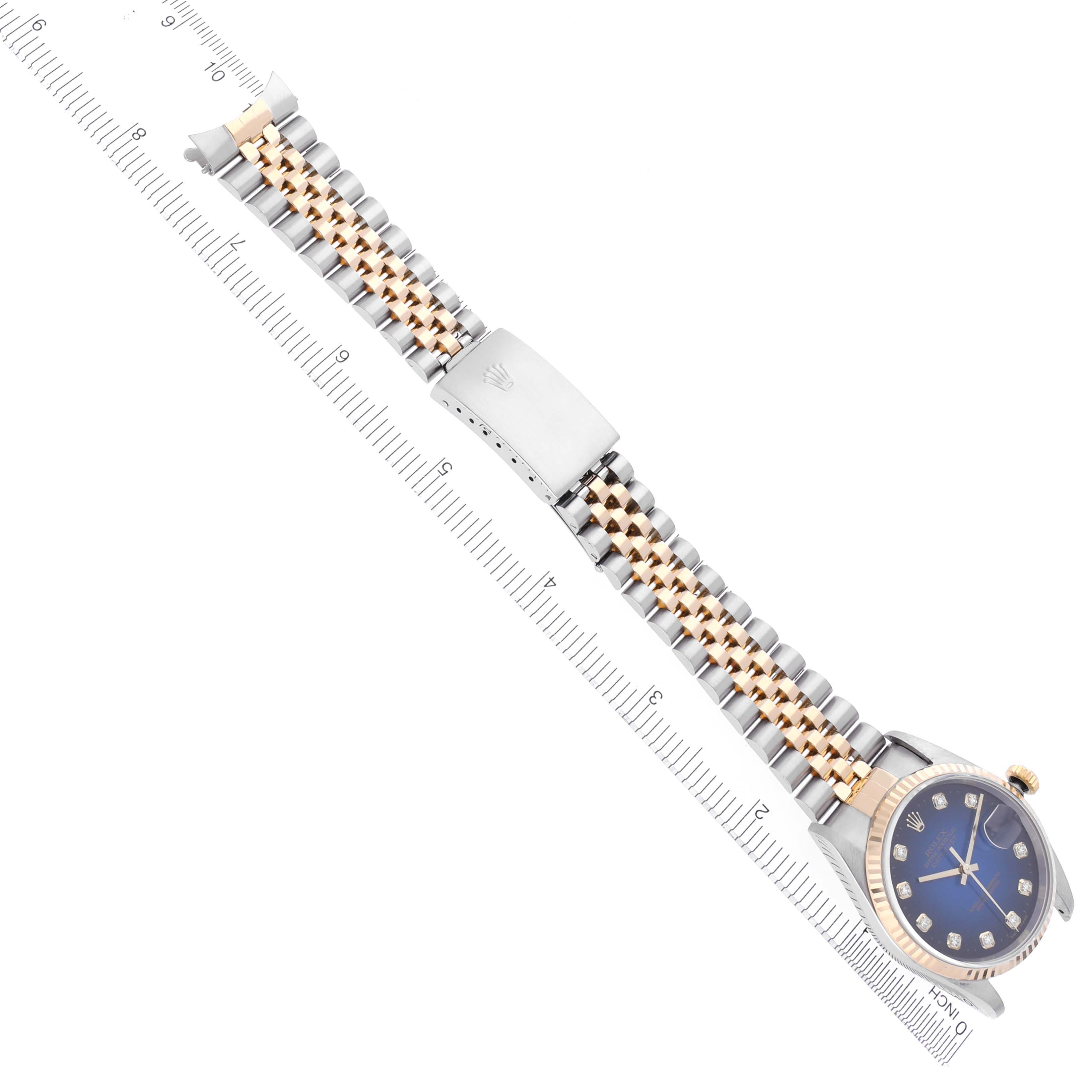 The Rolex Datejust 16233 Men's Steel and Gold (two tone) Blue Dial 16233 Men's Steel and Gold (two tone) Blue Dial watch is shown diagonally, displaying the bracelet, clasp, and face with a ruler for scale.