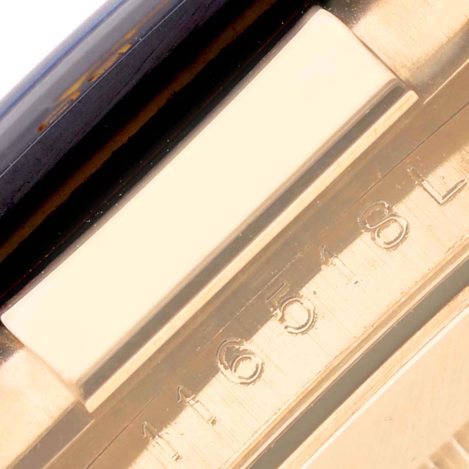 The image shows a close-up of the bezel and part of the case of a Rolex Daytona 116518LN Men's Yellow Gold Black Dial 116518LN Men's Yellow Gold Black Dial watch.