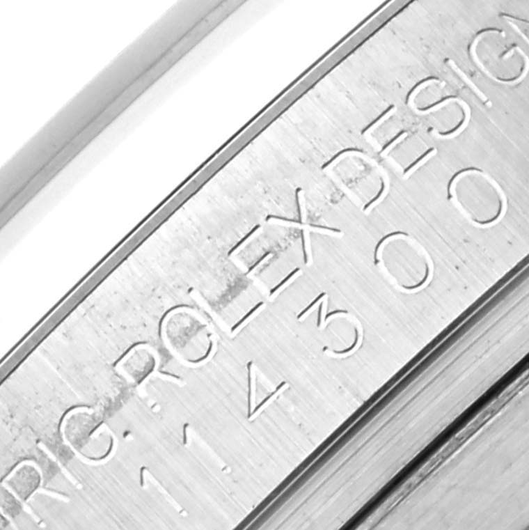 The image shows the engraved side of a Rolex Oyster Perpetual 114300 Men's Stainless Steel Grey Dial 114300 Men's Stainless Steel Grey Dial's case, displaying model and design information.