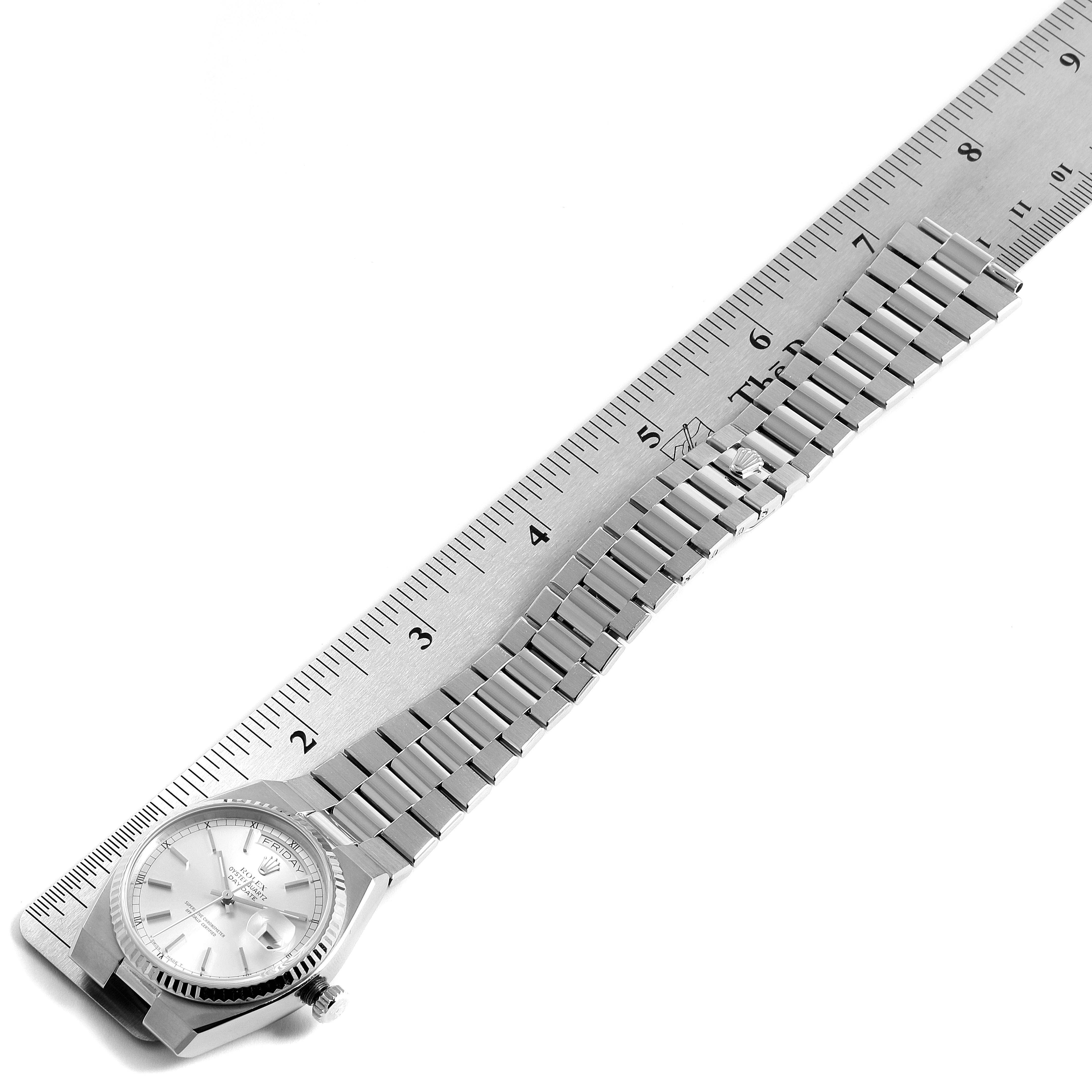 The image shows a Rolex Oysterquartz 19091 Men's White Gold Silver Dial 19091 Men's White Gold Silver Dial watch at an angle, featuring its face and metal bracelet next to a ruler for scale.